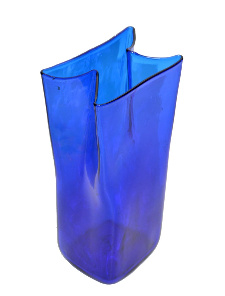 Blenko blue Mid-Century Modern hand blown art glass vase, vessel, geometric shape made in the 1980s.
The sculptural blue glass body looks stunning with every turn.
No markings.