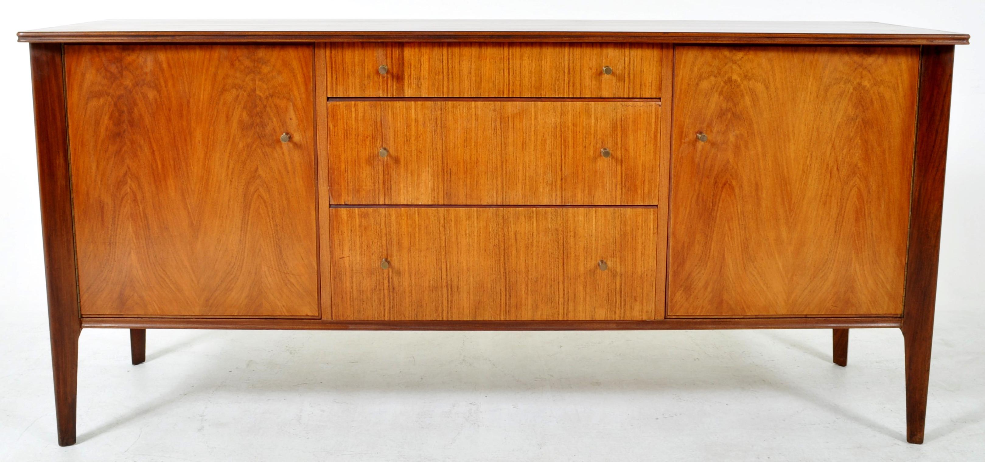 Original Mid-Century Modern (MCM) Danish Teak Credenza by A. Younger Ltd, 1960s. The credenza having a central bank of graduated drawers with original bronze pulls and flanked to either side by a cupboard enclosing a single shelf. The credenza