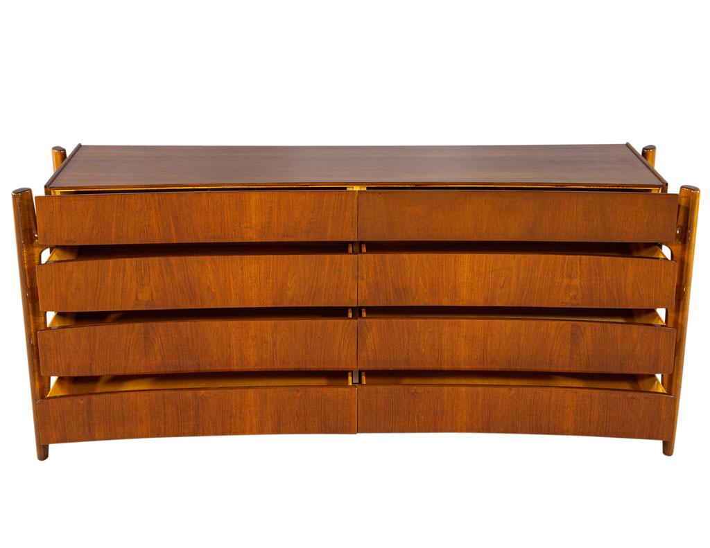 This original Mid-Century Modern dresser is a timeless piece of furniture, designed by the renowned William Hinn in the 1950s. It has a curved, Mid-Century Modern design, with beautiful wood grains and a Classic, iconic original finish. This piece