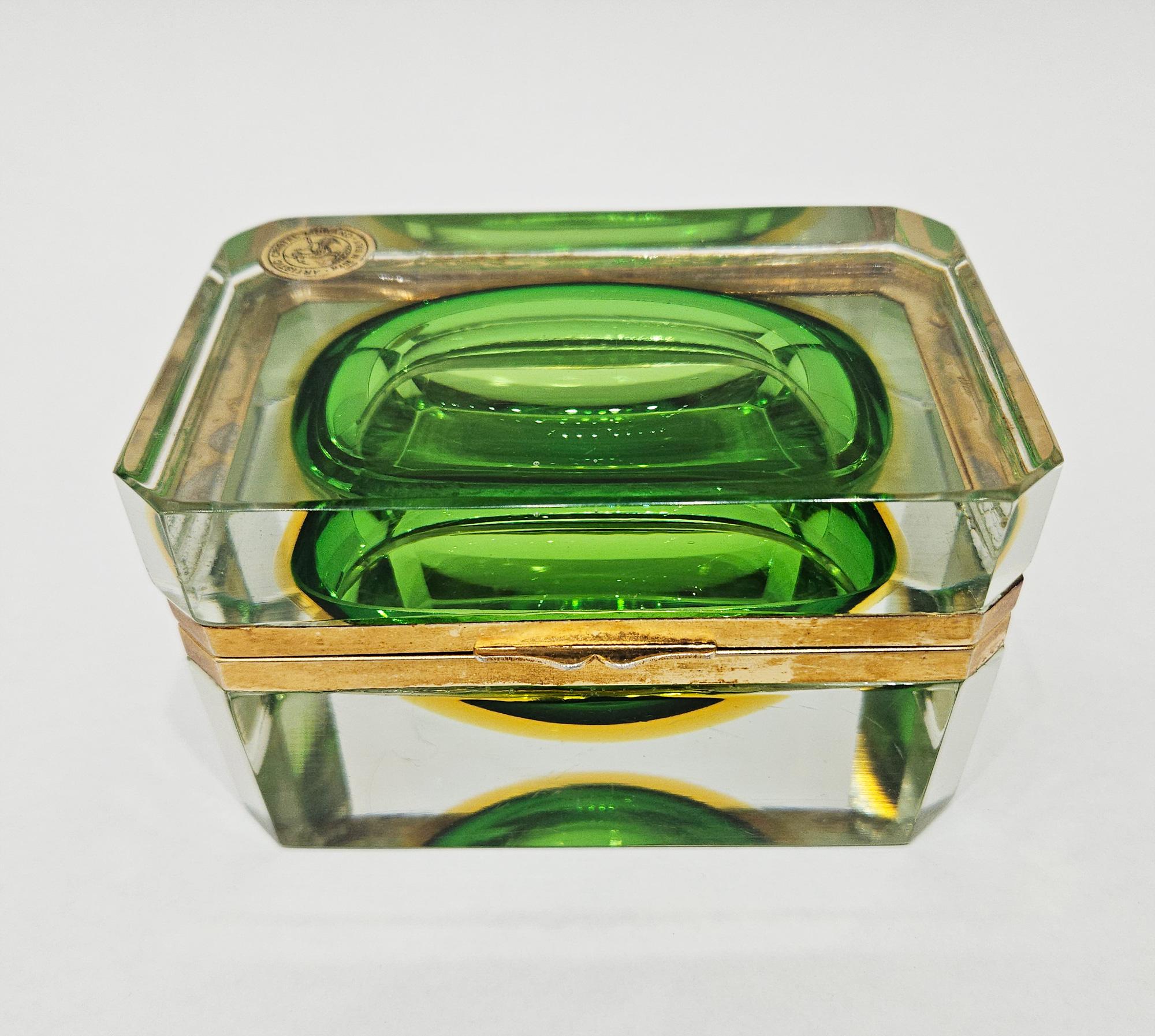 A gorgeous authentic and original emerald green and gold sommerso Murano glass casket, made in Italy c. 1960 and retaining its original label for Bucella Cristalli of Murano, Venice.

This decorative Italian art glass jewelry box is made with the