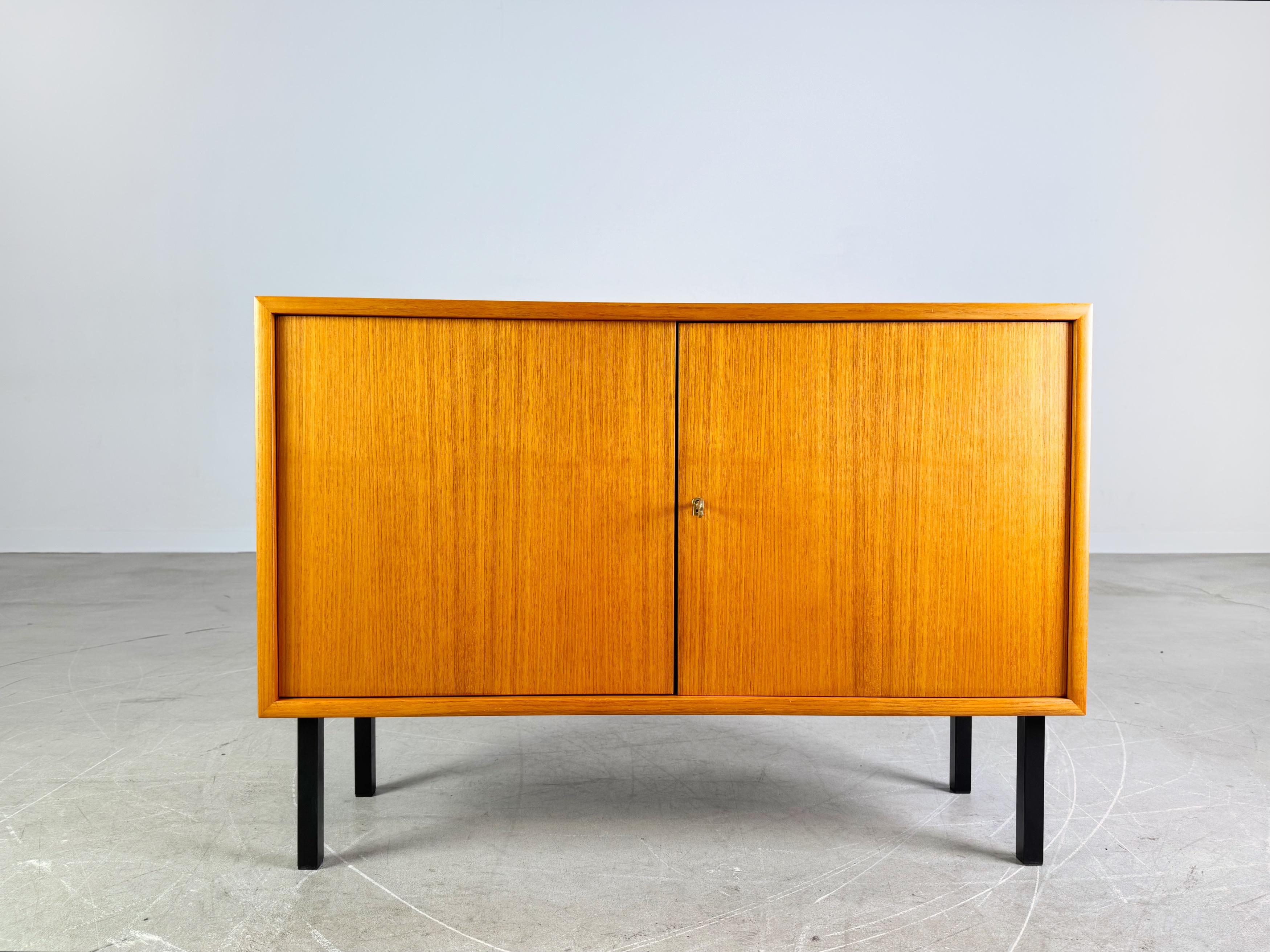 Wir bieten ein wunderschönes kleines Teakholz Sideboard/ Anrichte aus den 1960er Jahren zum Verkauf an. Das Möbel verfügt über zwei abschließbare Türen und lässt sich aufgrund seines minimalistischen Designs sehr gut in moderne Wohnräume