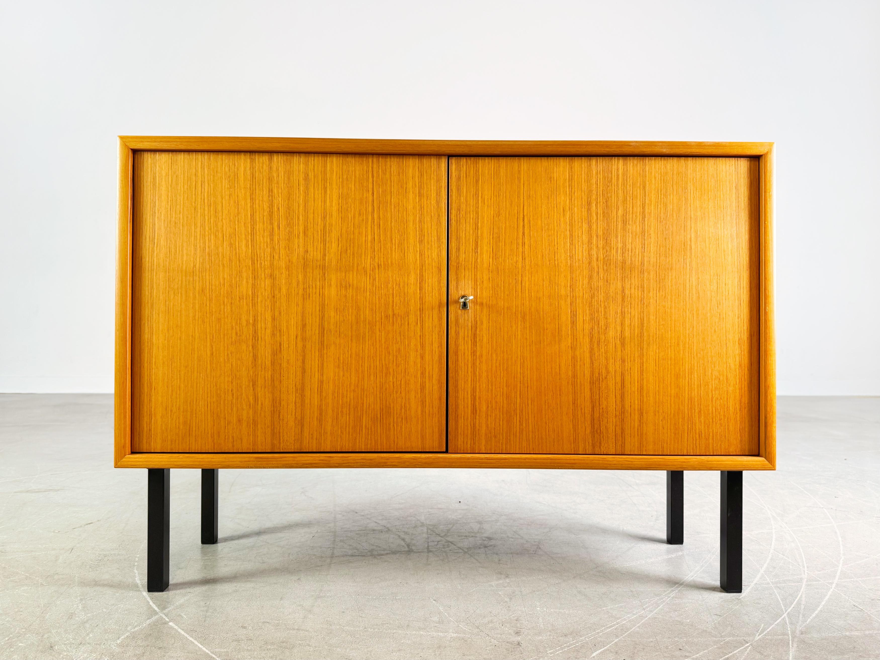 Wir bieten ein wunderschönes kleines Teakholz Sideboard/ Anrichte aus den 1960er Jahren zum Verkauf an. Das Möbel verfügt über zwei abschließbare Türen und lässt sich aufgrund seines minimalistischen Designs sehr gut in moderne Wohnräume
