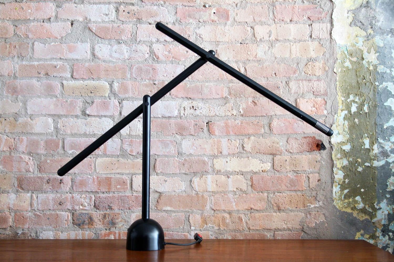 This is a mira table lamp designed by Mario Arnaboldi. Production of this lamp was very limited. This piece is in black enameled metal. Its arms can be adjusted and moved into a variety of positions emphasizing the angular aspects of the design.