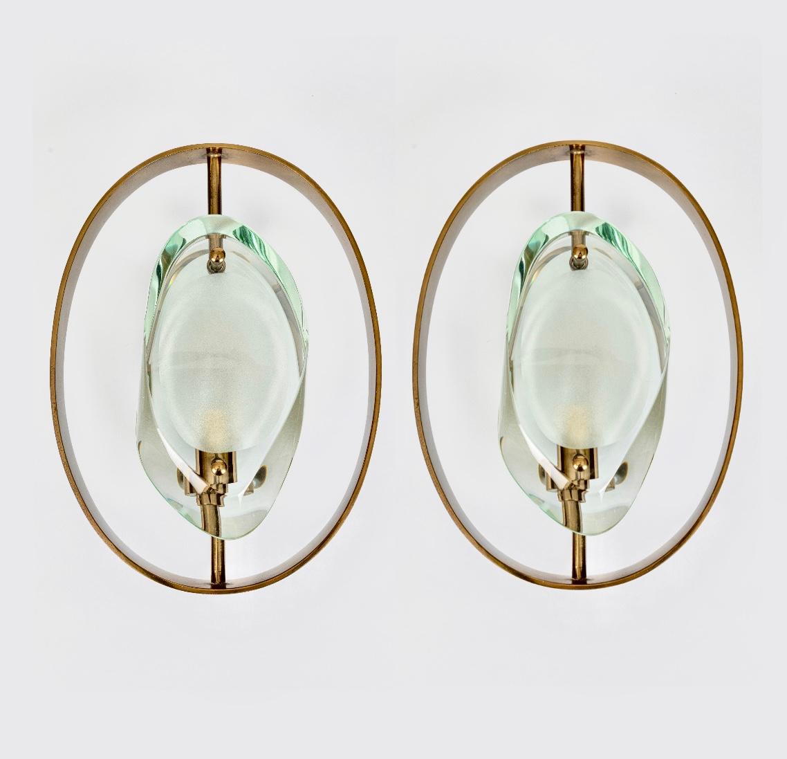 An original and rare pair of Mod. 2240 'Micro' wall lights by Max Ingrand for Fontana Arte, Italy, c.1961. The Micro design features a sleek oval brass frame that surrounds two profiled glass diffusers, each with a concave acid-etched centre which
