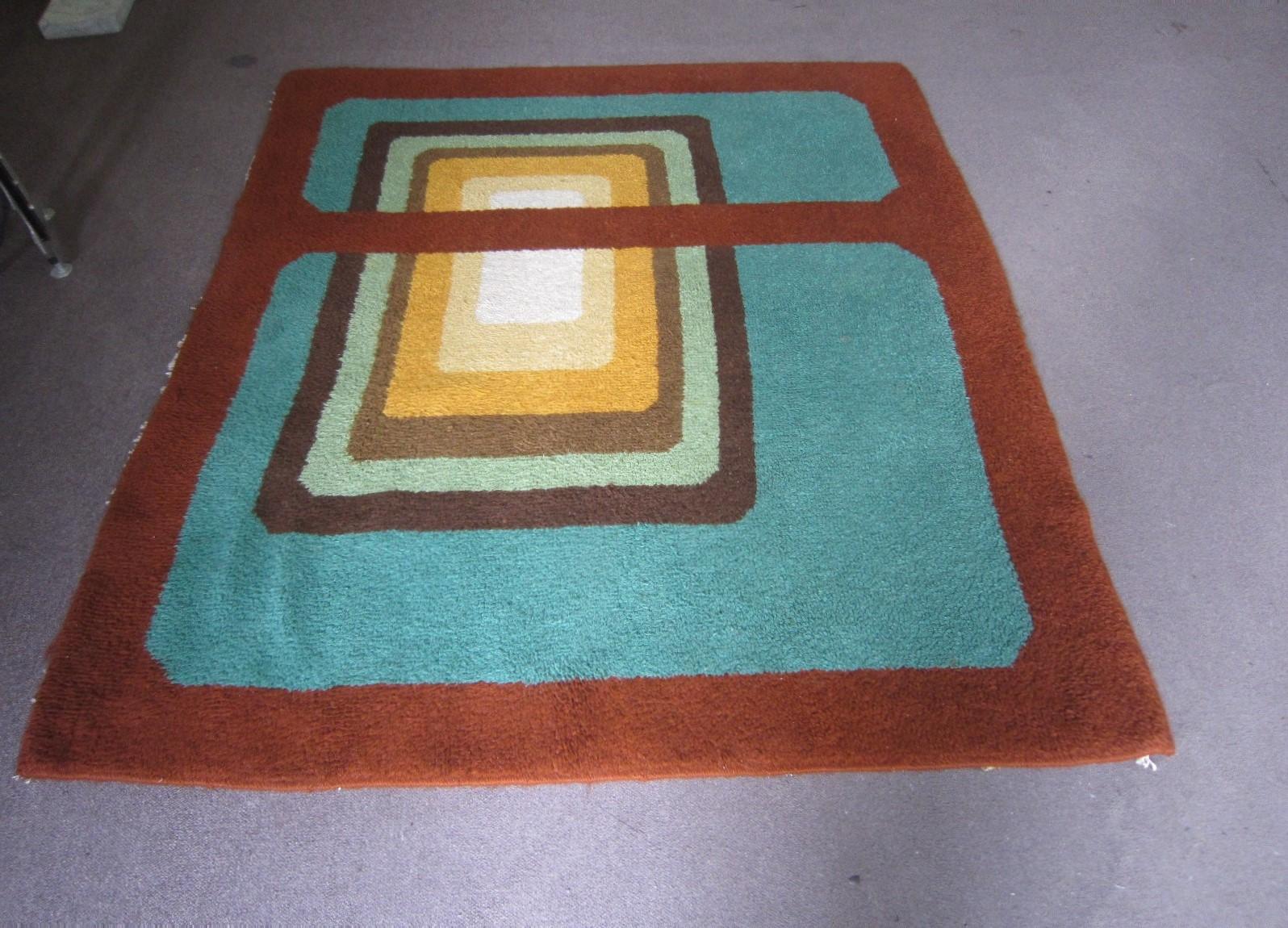 Abstract bold patterned geometric, vintage carpet in colorful shades of russet, greens, ochres, gold, browns.
Square and rectangular overlays and color blocking represented on this Mod design.
This decorative carpet was made when it was still a