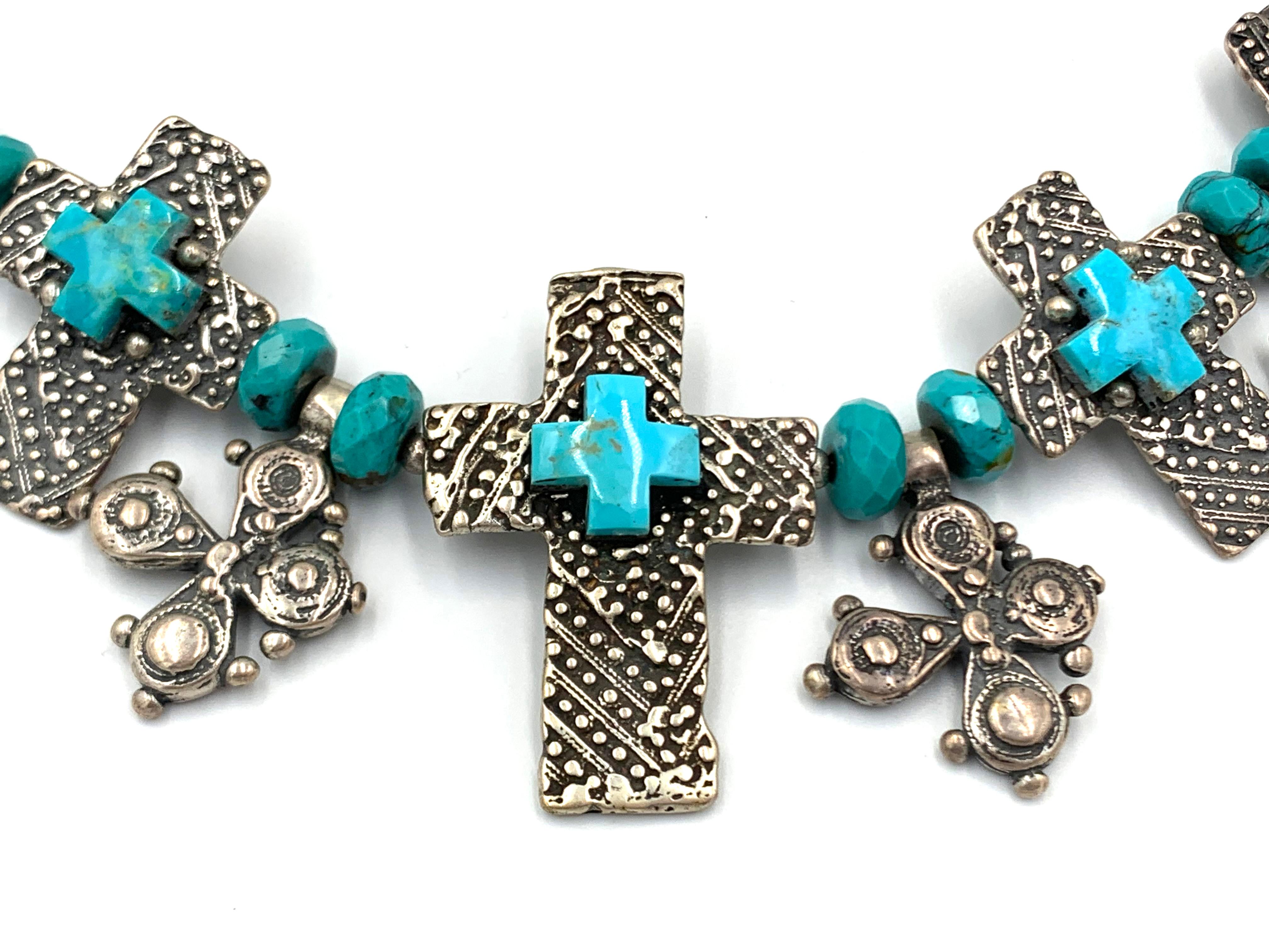 Congiunzione di croci, molte croci si uniscono con rondelle di turchese e catena in sterling. Questo splendido pezzo è un'ampia collana realizzata con perline turchesi e un punto focale di pendenti a croce in argento sterling. 

Mary e Doug