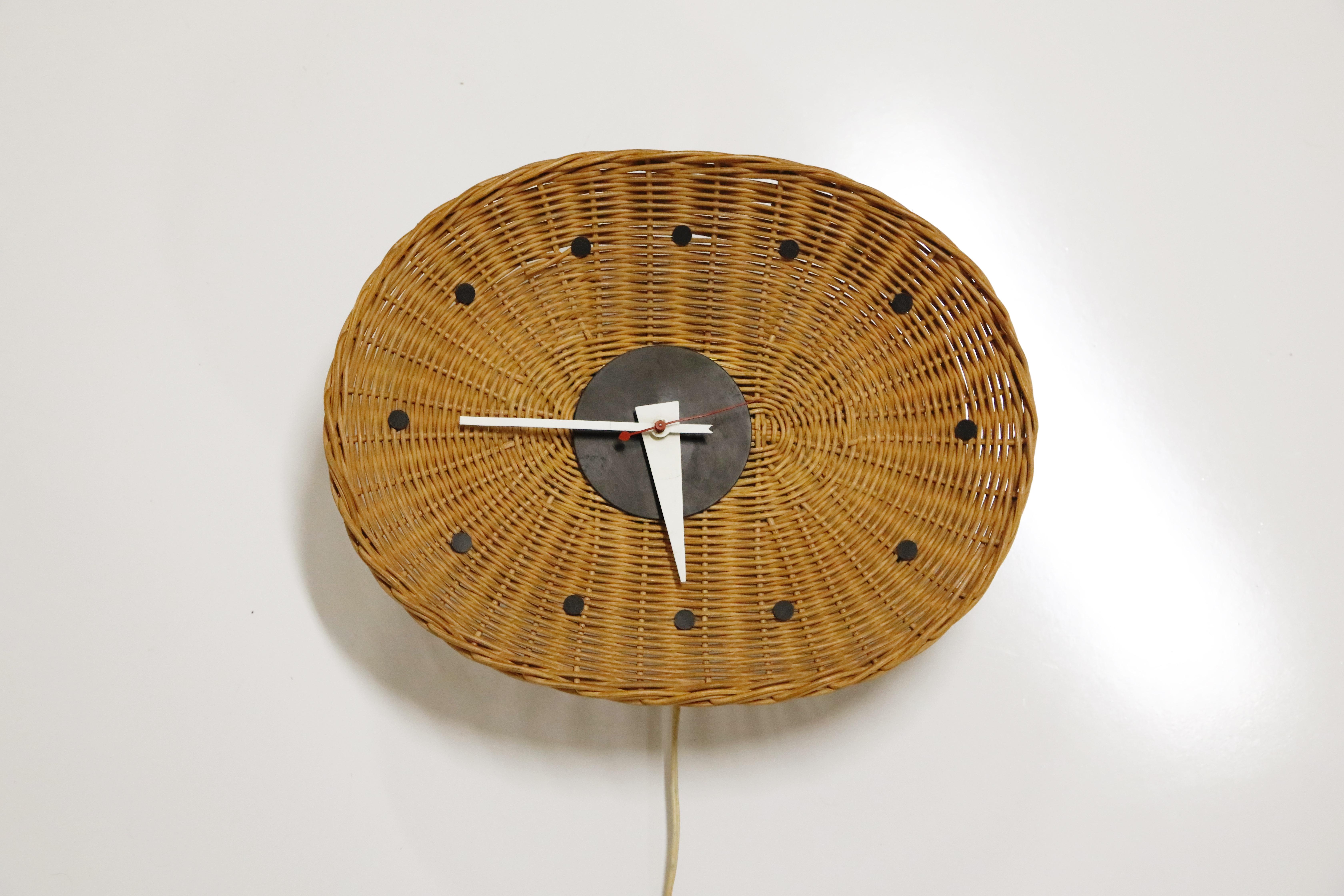 Out of the 150+ designs created by George Nelson for Howard Miller, this Oval 'Basket' wall clock is one of the more rare editions. Small black circles mark the number positions around the oval, woven wicker-basket clock face. From the center, the