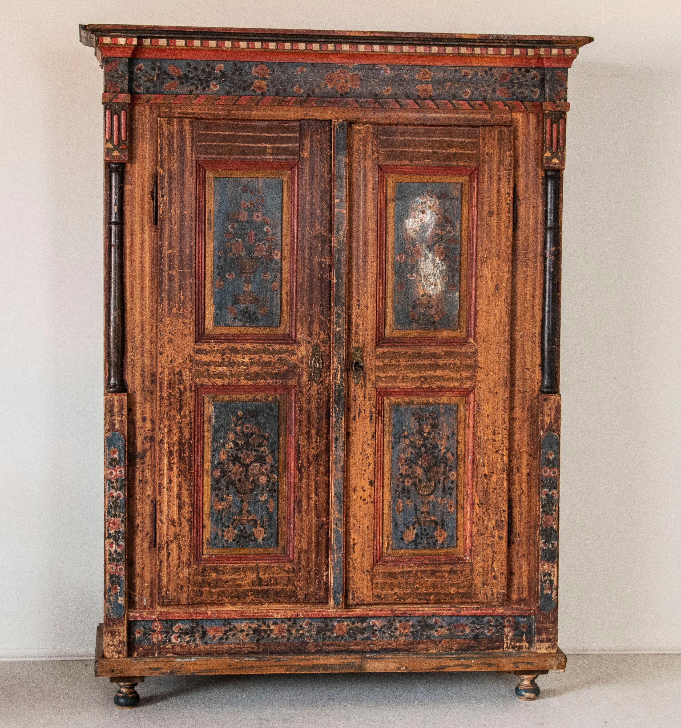 This delightful armoire was considered exceptional in its day, with the elaborate hand-painted details requiring a professional painter to invest a tremendous amount of time to complete. While it has grown worn and faded over time, it is precisely