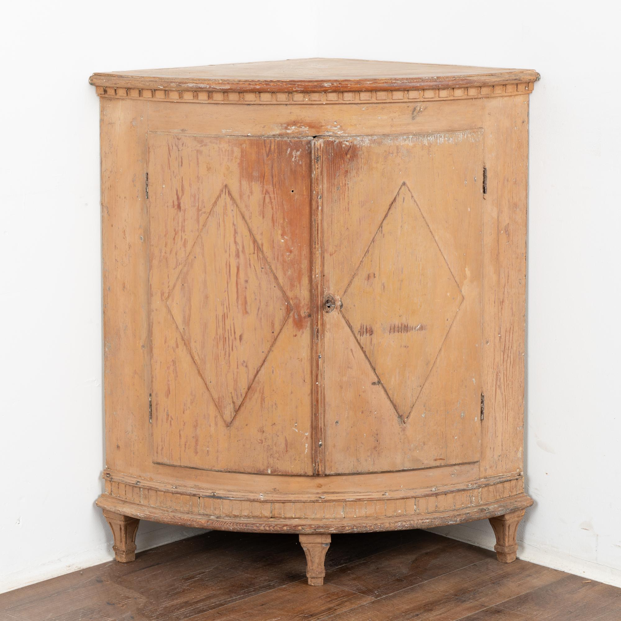 Low corner cabinet from Sweden with original buff colored paint, distressed throughout revealing the natural pine below.
Traditional diamond motif on panel doors, bow front exterior and dentil molding. Rests on tapered fluted feet.
Restored, this