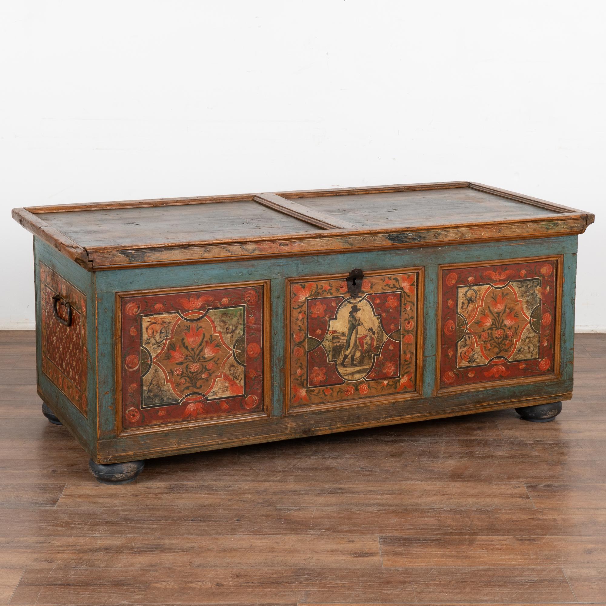 The colorful paint is all original on this beautiful flat top trunk. Exceptional detail is seen in the floral side panels, central panel with figure of man serenading reclining woman, vibrant borders and more.
This trunk has original wrought iron