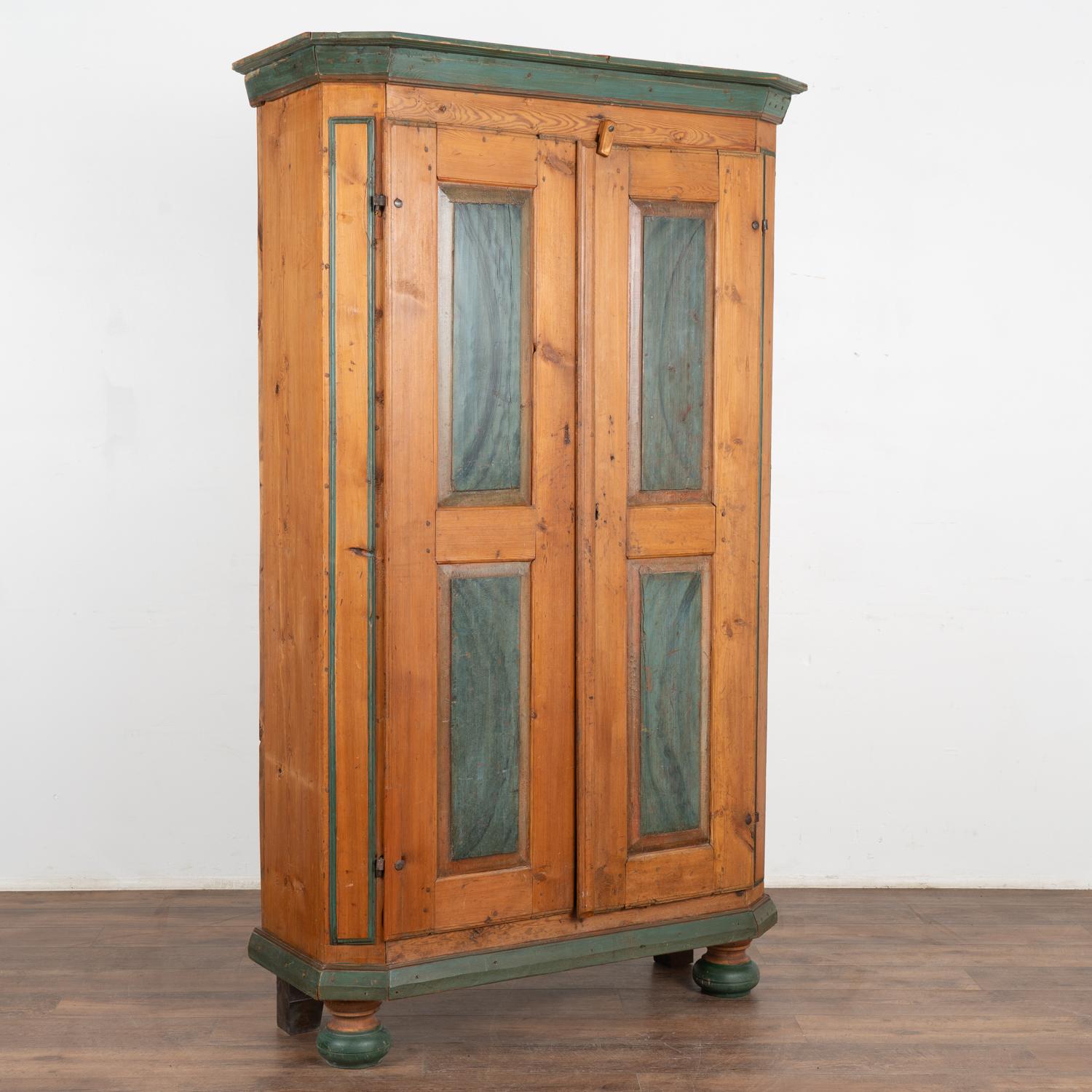 This narrow armoire from the Swedish countryside shows off its age in the warm, deep patina of the natural pine and stands 6.5' tall. 
The original hand-painted teal blue panels were painted in the folk art style of the era, along with decorative