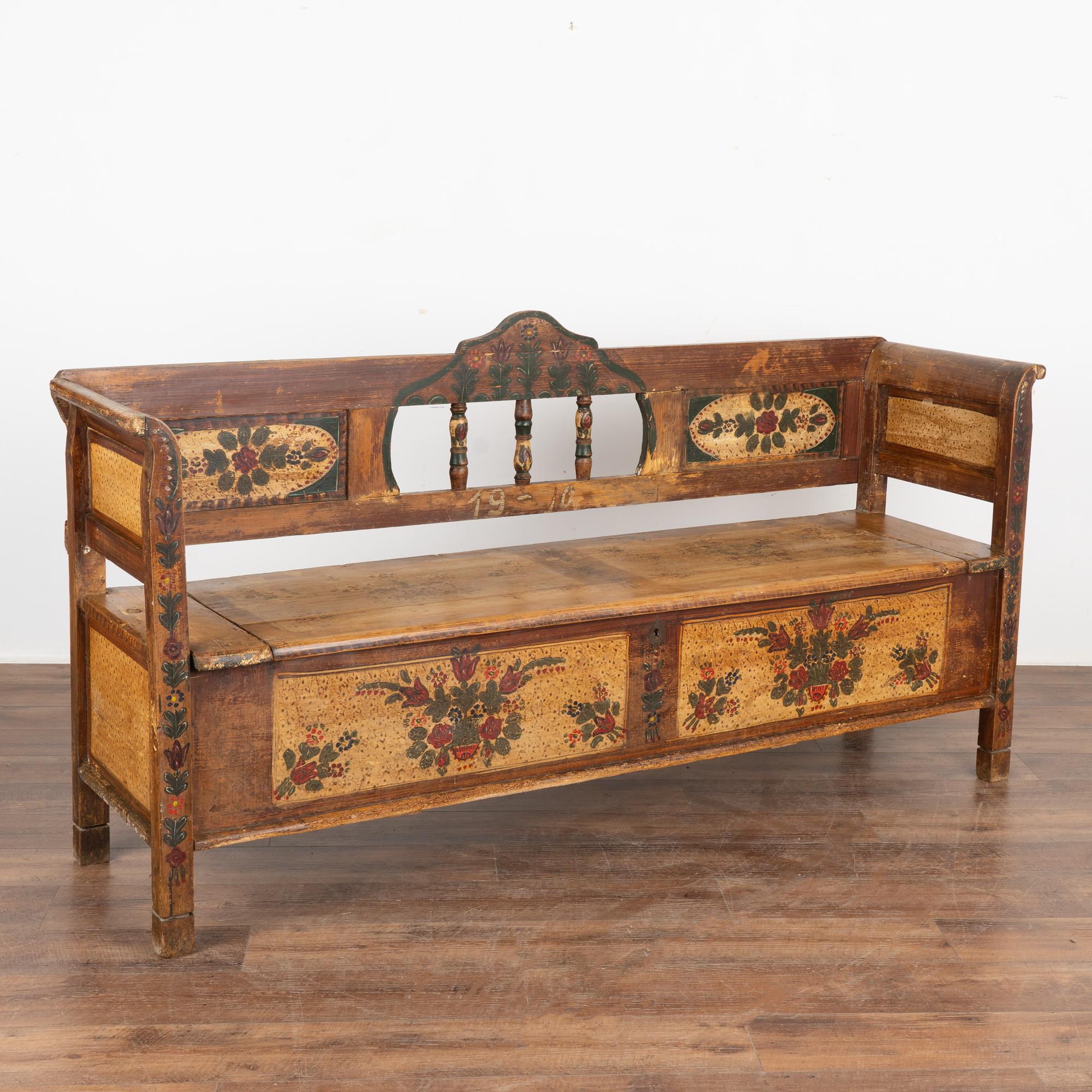 Original hand painted folk art pine bench displays traditional brown faux wood background and colorful floral displays within painted panels in back and front.
Hinged bench seat opens to reveal interior storage.
Restored, cleaned and waxed, this