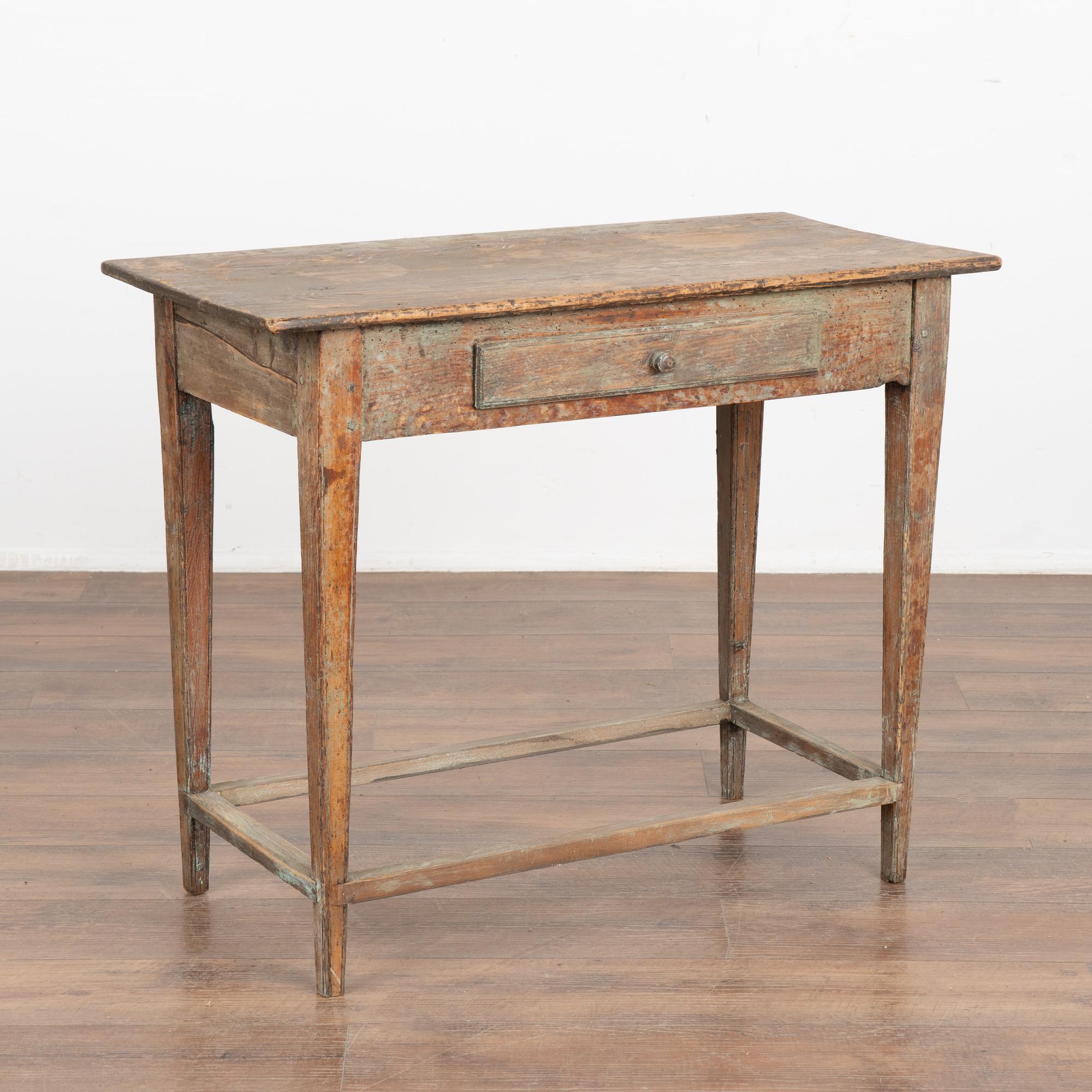 Swedish country original painted pine side table with traditional tapered legs and single drawer. 
The original paint has been worn down to the warm pine patina below. Faint remains of blue/green/teal paint are visible along with the scratches,
