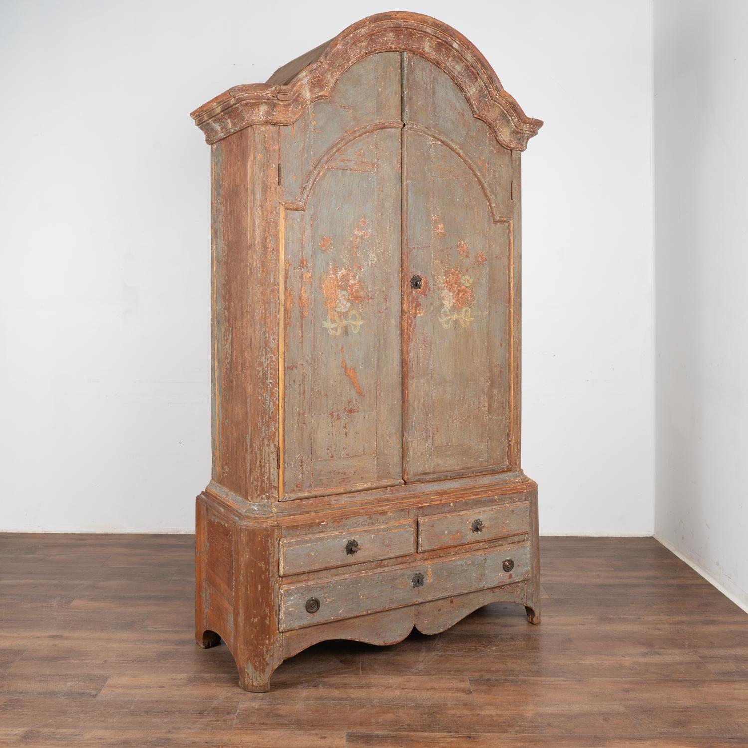 Original painted Swedish wedding cabinet from the early 1800's with floral bouquet on each door.
Note the traditional curved and carved upper bonnet, two cabinet doors over three lower drawers, four interior shelves and upper spoon rack.
Layers of