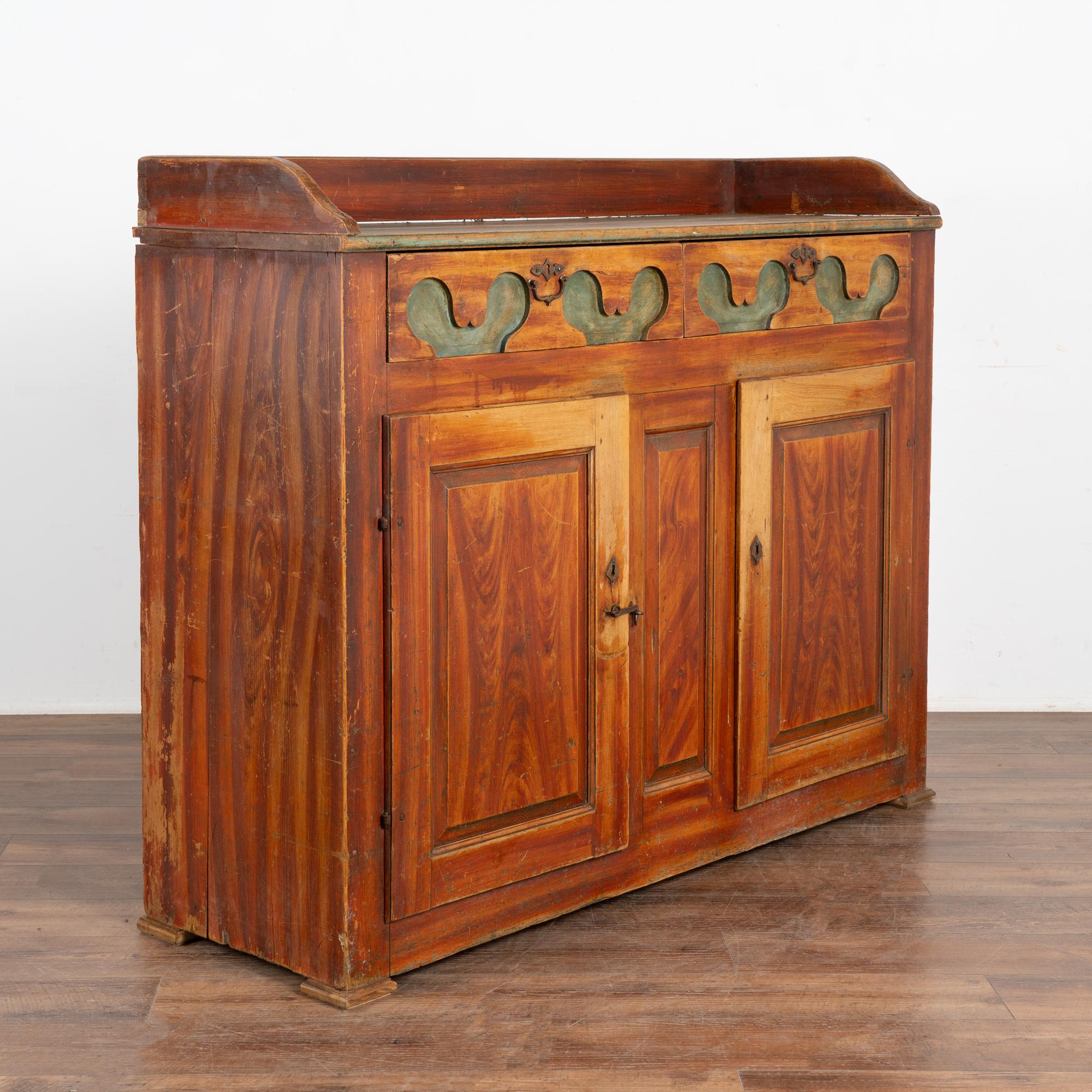 This pine sideboard is a wonderful example of Swedish country craftsmanship with unique carving along the two drawers.
The faux wood painted background was the folk art style of the period. The drawers and buffet top are painted in a contrasting