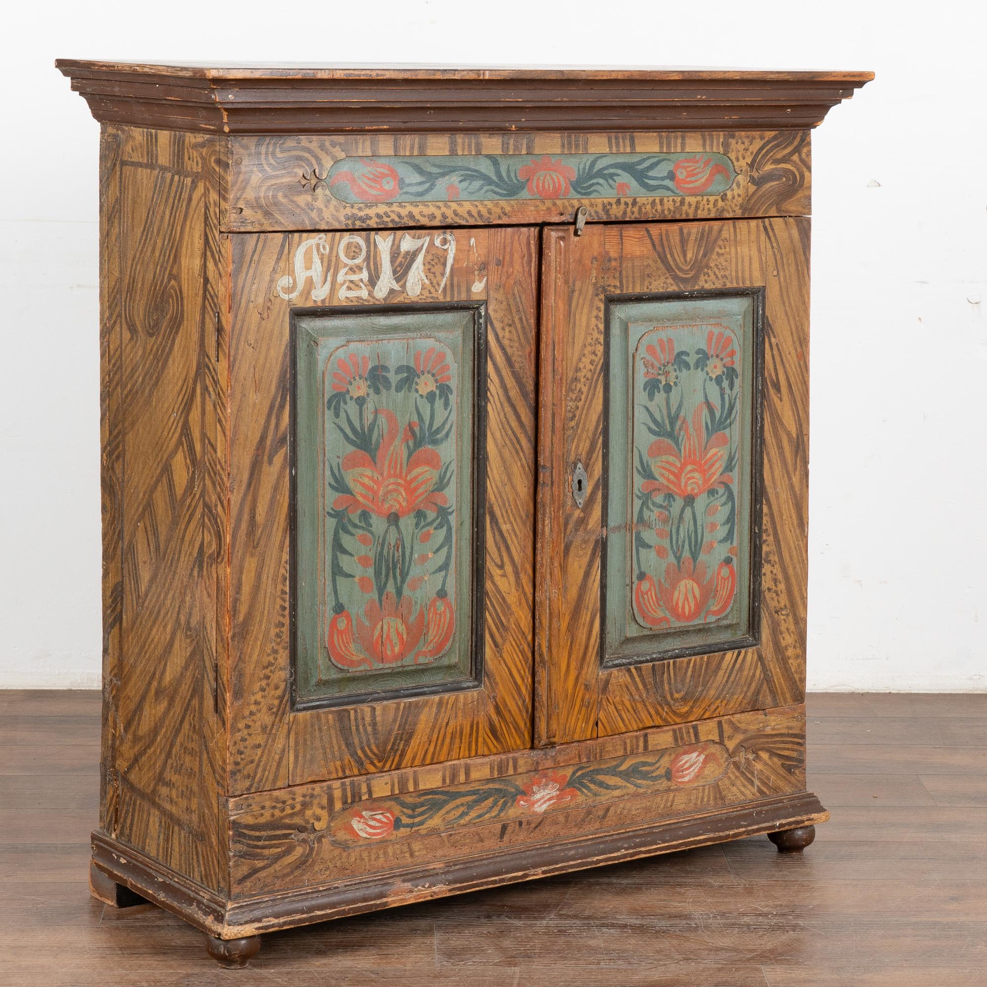 While you can frequently find original painted Swedish trunks, it is difficult to find a cabinet or sideboard with exceptional original folk art paint such as this one.
The two panel doors are painted with a traditional floral motif against a faux