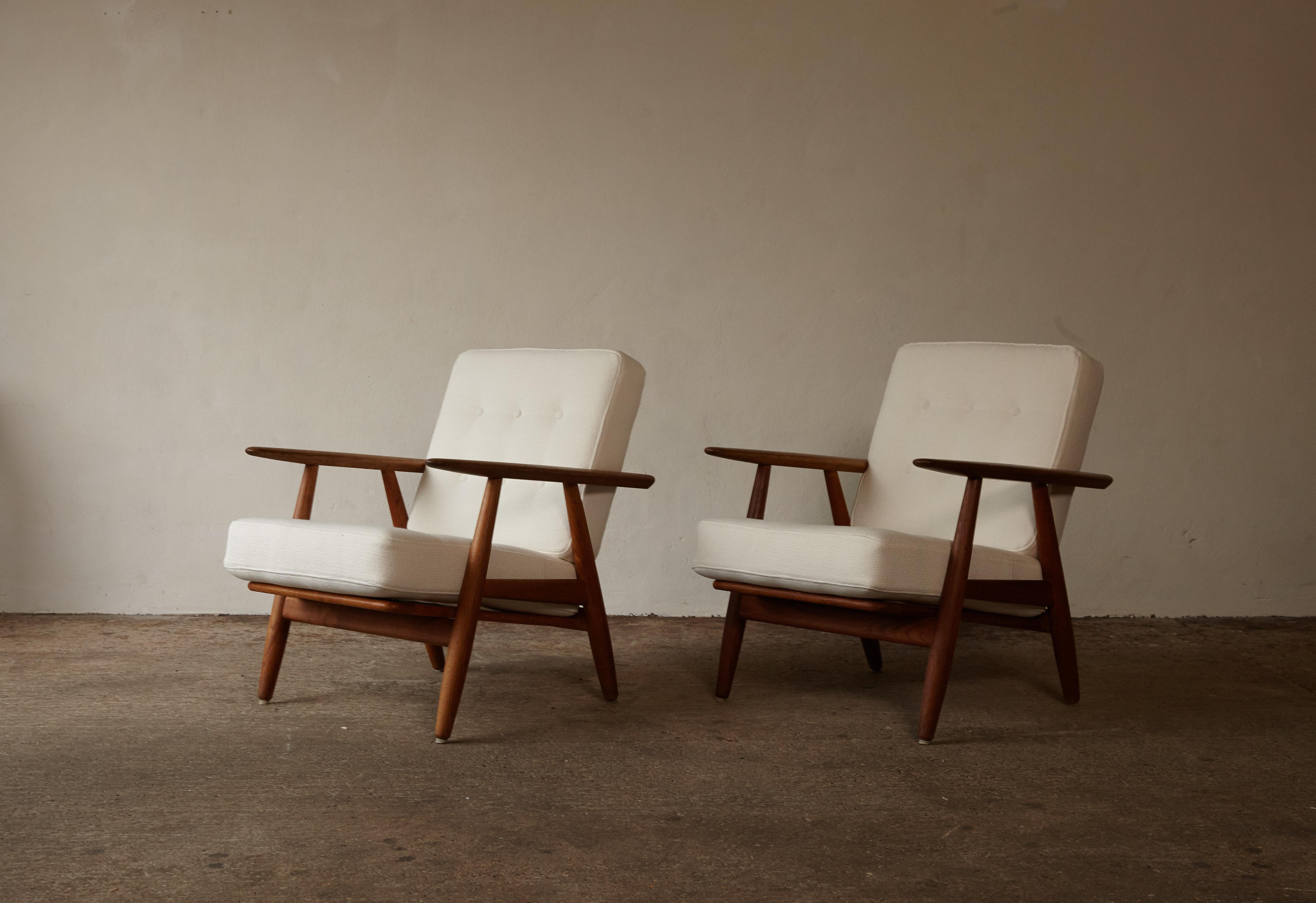 A pair of oak GE-240 cigar lounge chairs designed by Hans J. Wegner and produced by GETAMA, Denmark. The oak frames are in very good vintage condition with only very minor signs of age and use. Original sprung cushions re-upholstered in a high
