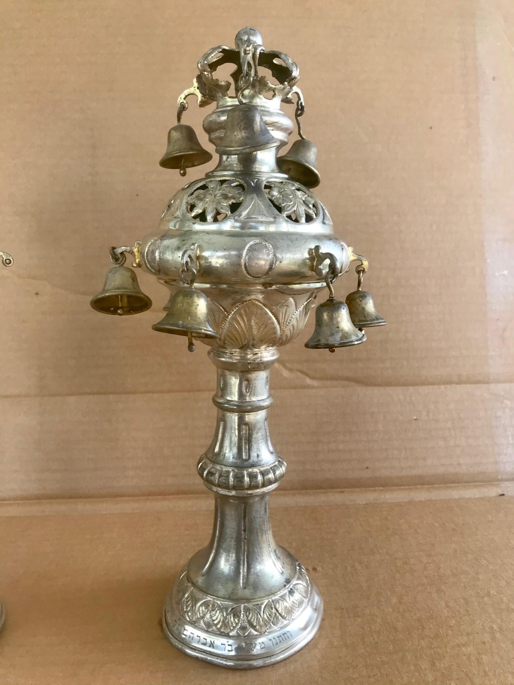 Antique original pair of silver plated brass torah finials, Rimonim

The pair of finials have bulbous stems and spherical upper sections that are hung with bells. Each is topped with a crown and knob. Delicate repoussé and engraved designs mark