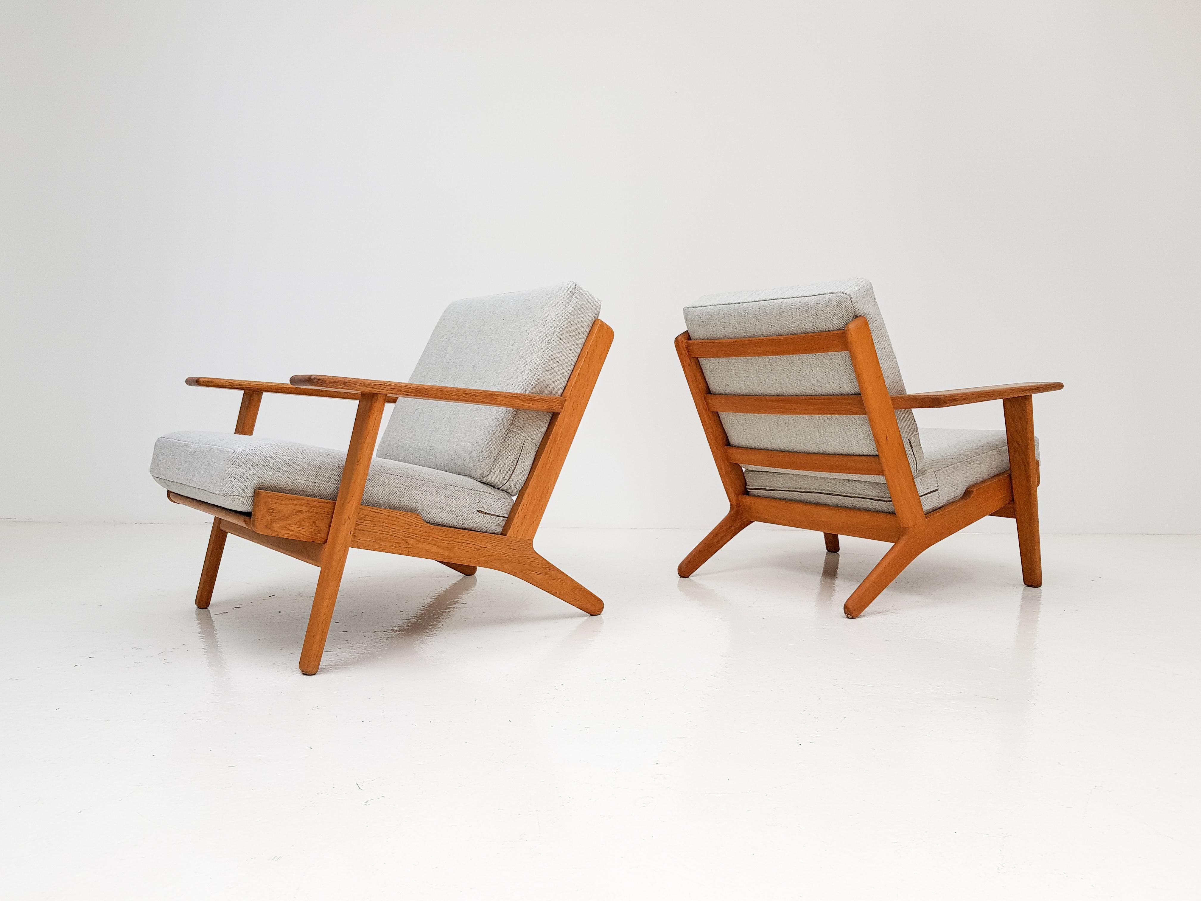 An original pair of iconic Hans J. Wegner GE290 oak framed 'plank' armchairs designed in the late 1950s and produced by GETAMA, Denmark. 

The pieces feature new Kvadrat Hallingdal 65 upholstery and original sprung cushions and have a traditional