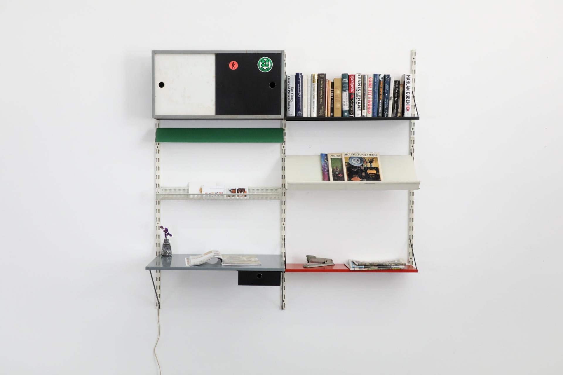 Dutch Mid-Century, Pilastro enameled metal wall unit in very original condition with desk, cabinet, perforated basket, shelves and magazine rack. This unit features a gray enameled desk and cabinet with black and white enameled sliding doors, a