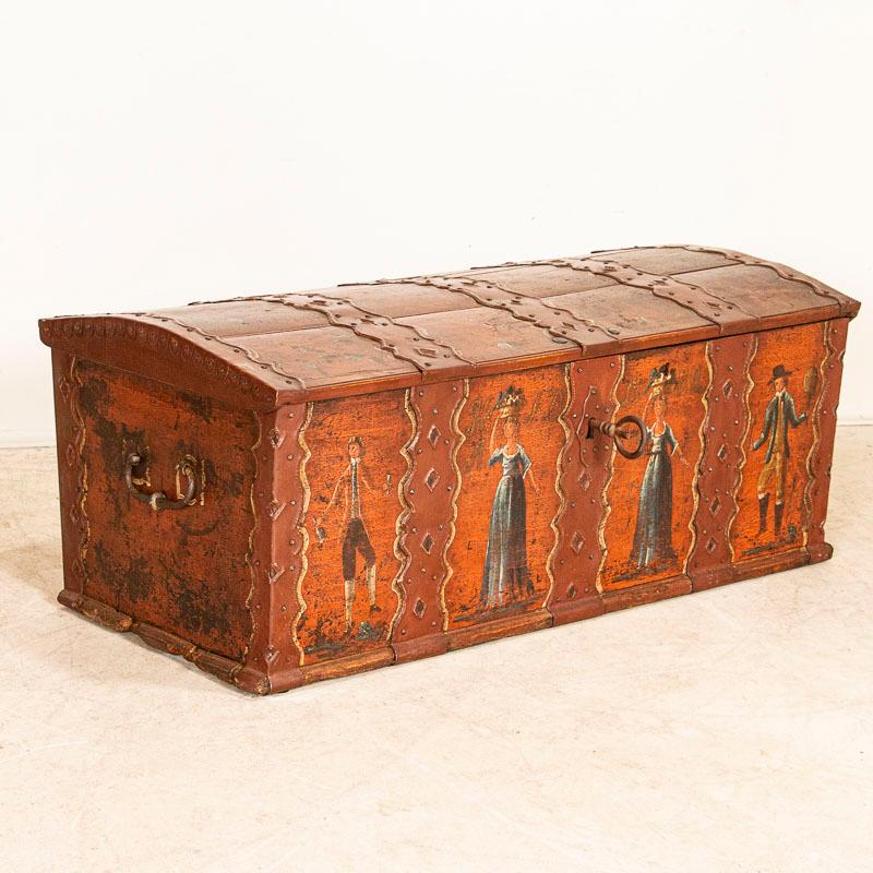 This unusual domed top trunk from Sweden is a rare find. The original brick red paint remains along with the delightful figures of two ladies and two gentlemen which make this trunk quite special as most folk art of the era was composed of floral