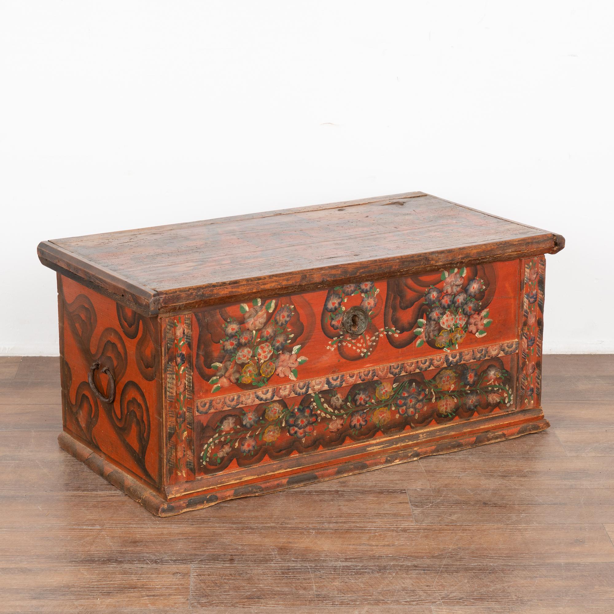 Original hand-painted folk art flat top pine trunk.
Original traditional floral motif painted finish in red/burnt orange, brown/black, yellow and green.
Restored and waxed, in solid condition ready to use. Original hand-wrought iron hinges and side