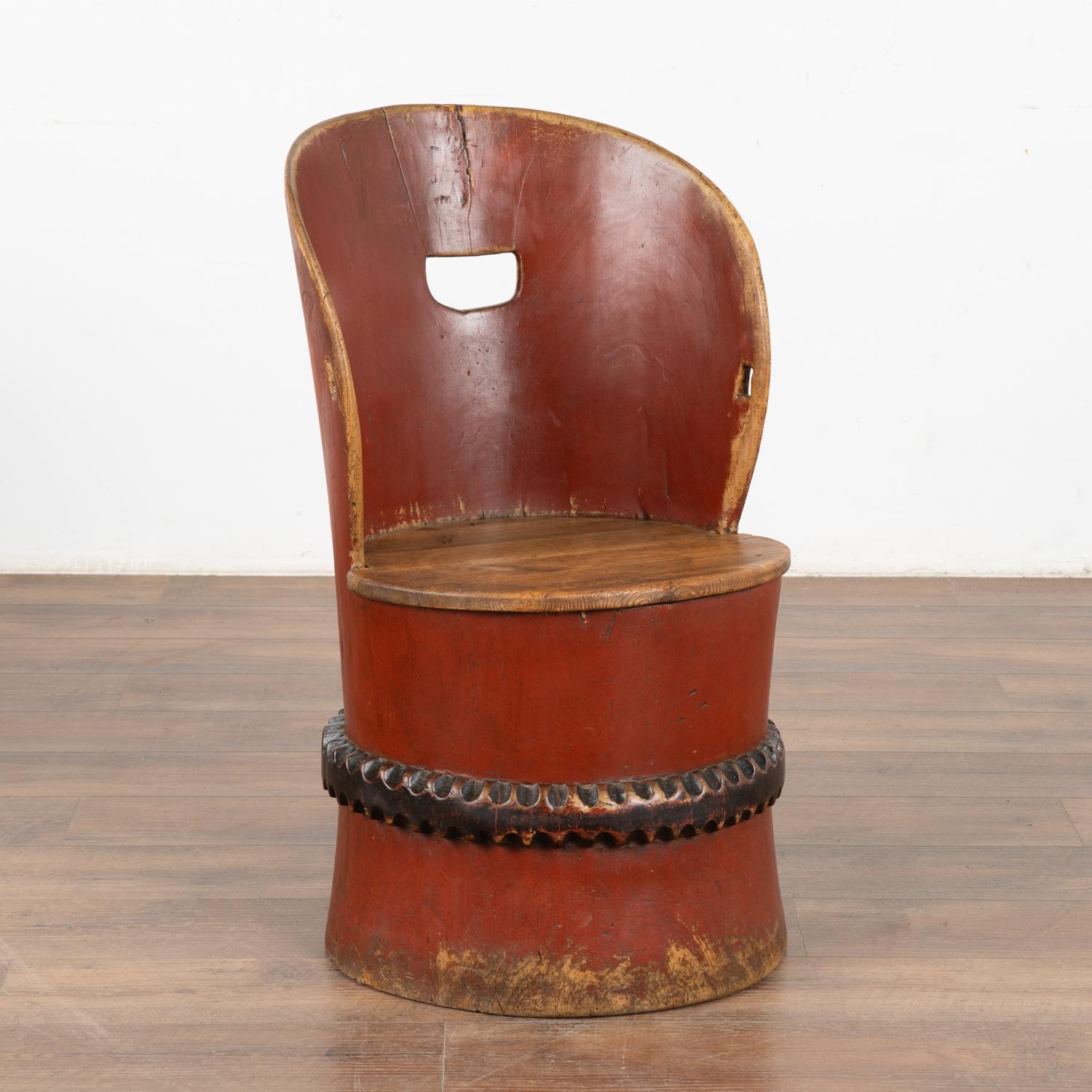 Antique carved and painted kubbestol, a traditional Scandinavian chair crafted from a single log.
The lovely original red paint is accented by a carved and black painted band. Much of the original finish is worn down to the natural wood below adding
