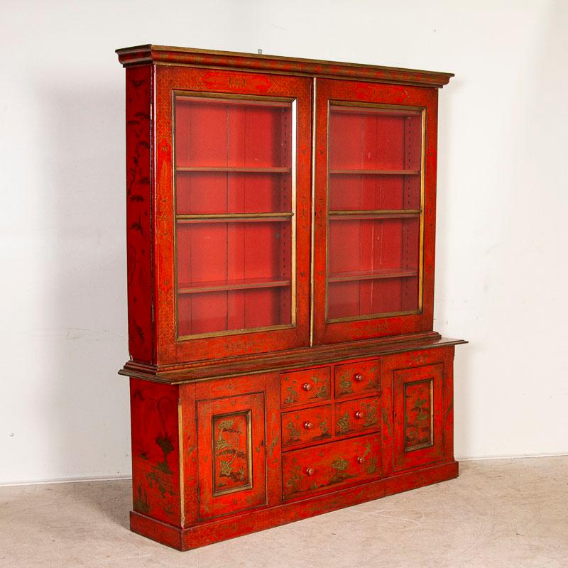 Absolutely stunning, this original red painted lacquered china cabinet still maintains dramatic gold painted birds, trees, butterflies and figures found throughout the casework. The interior shelves are adjustable, making this an ideal display