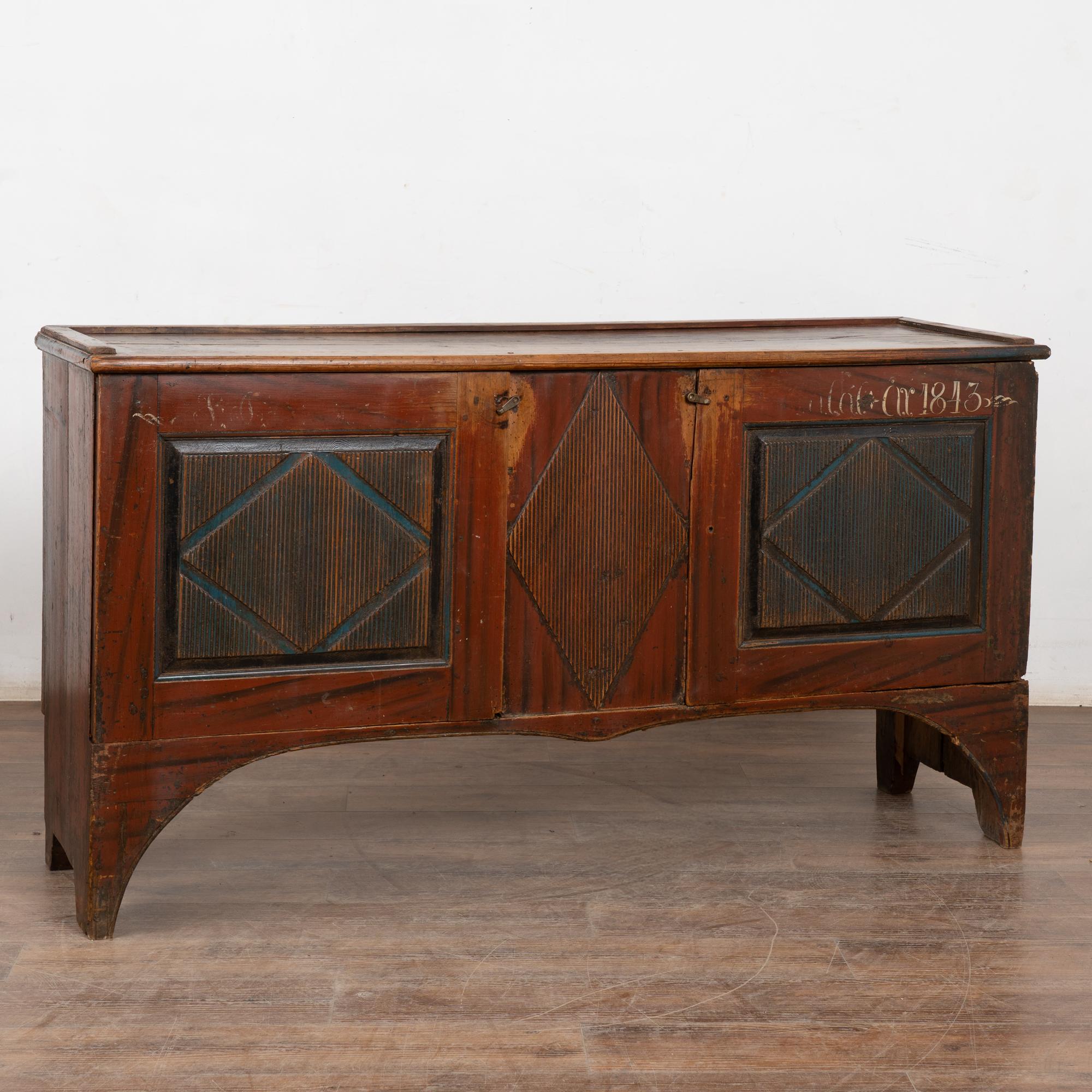 This original painted pine sideboard is a wonderful example of Swedish country craftsmanship with a warm, aged patina in the brick red painted finish with contrasting blue painted decorative diamonds. Note faded monogram and date of 1843 along right