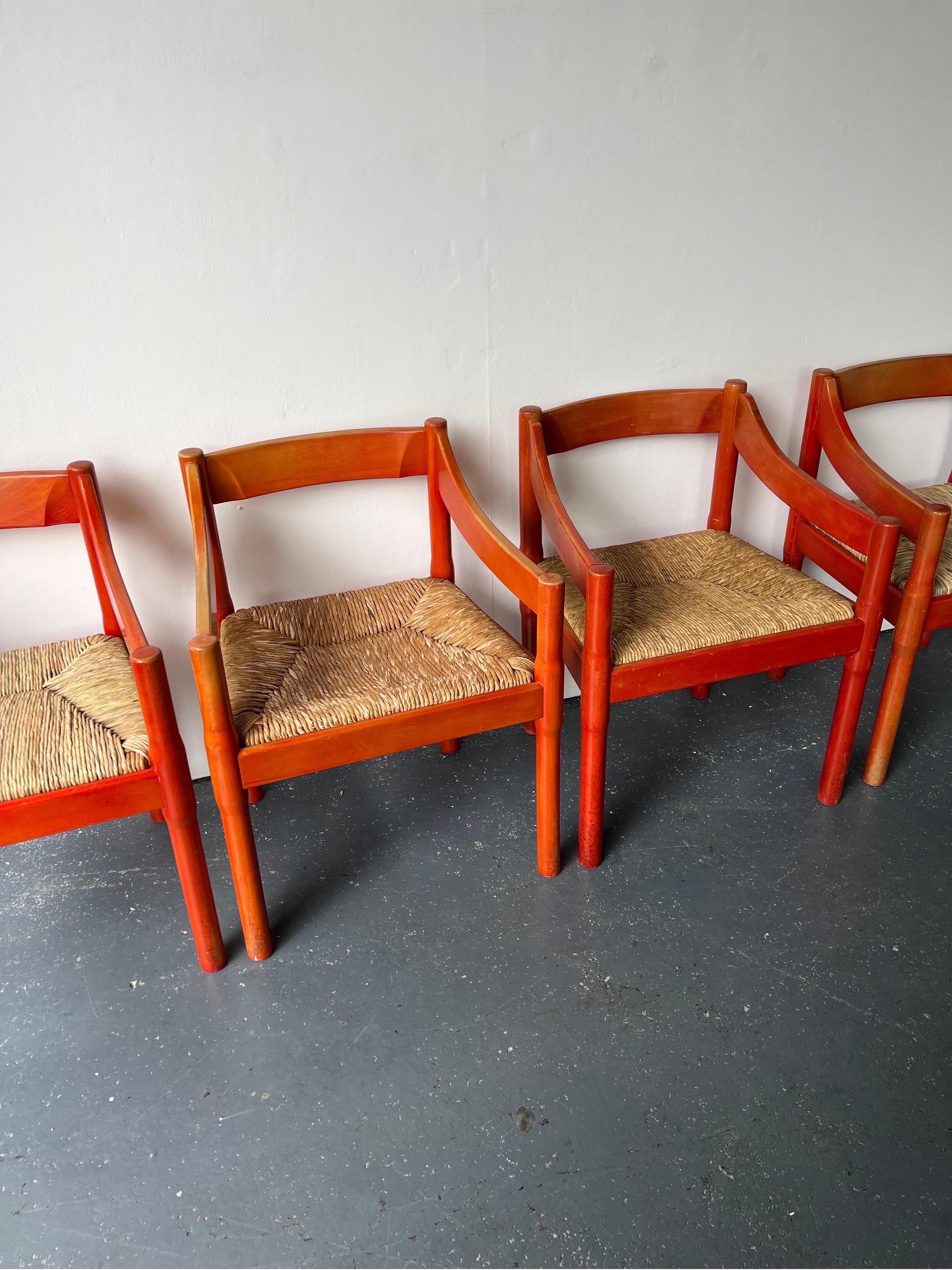 Charming set of x2 red-stained Beech Carimate chairs designed by architect and designer Vico Magistretti. These chairs have their original red stain from the 1960s which has faded in places and the fading may appear more so in certain areas than