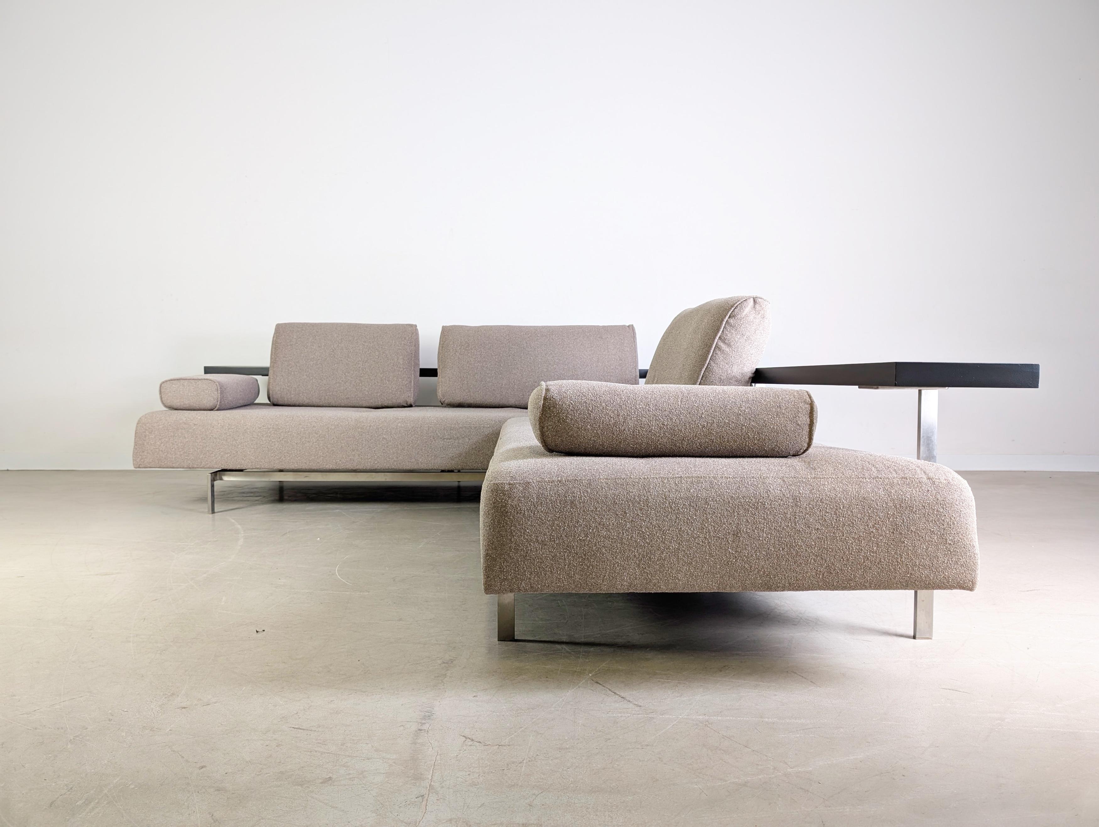 Wir bieten ein wunderschönes, komplett neu bezogenes Rolf Benz Dono 6100 Ecksofa zum Verkauf an. Das Sofa zeichnet sich aus durch seine moderne und praktische Rückenlehne/ Ablage aus Holz und verfügt über drei Rücken- und zwei Armlehnkissen, die
