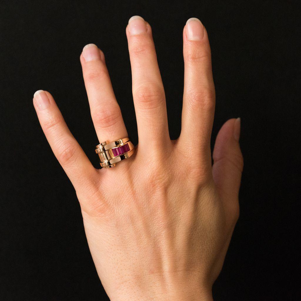 Ring in 18 carat yellow gold, eagle head hallmark. 
A voluminous and asymmetrical ring that features 5 synthetic calibrated rubies in invisible settings. 
Width: 1.7 cm, height at the top: 0.7 cm, ring width at the base: 6.5 mm.
Total weight of the
