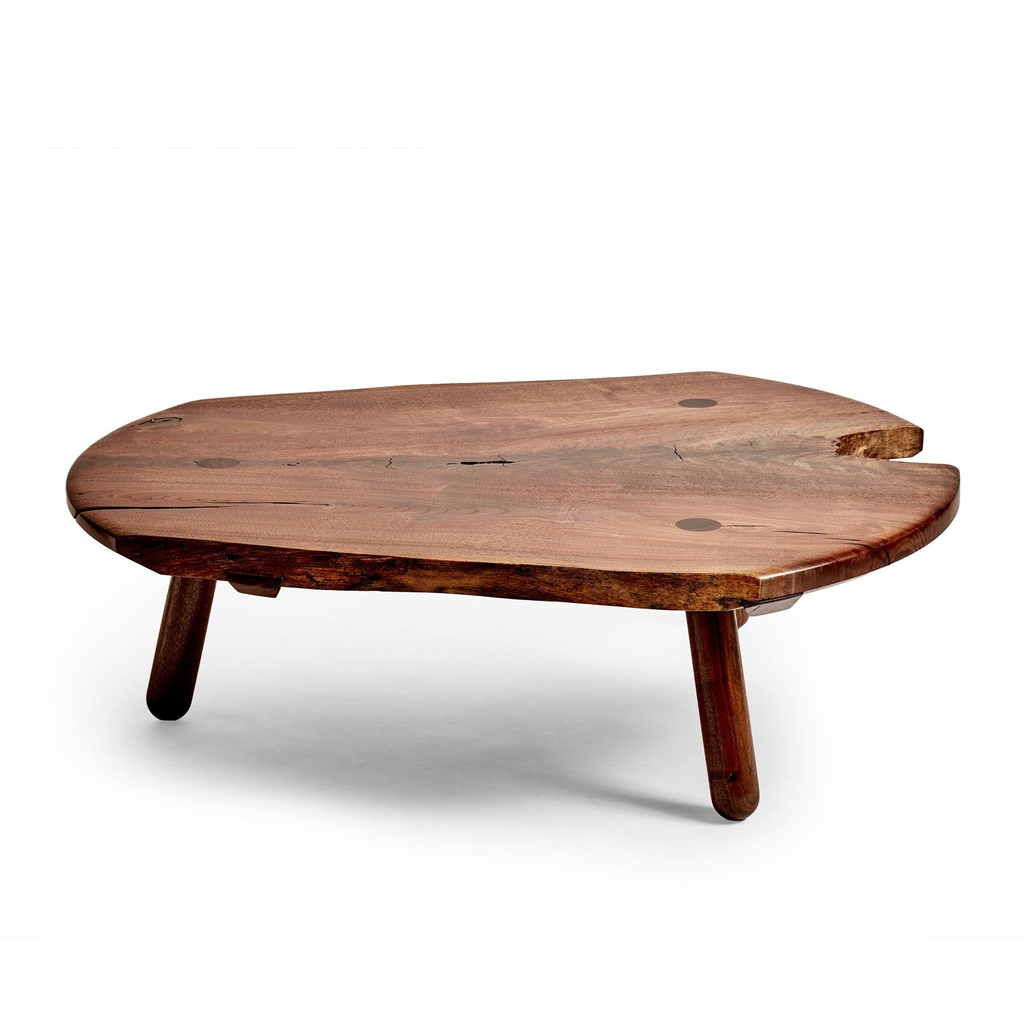 Una singular mesa baja de centro / cóctel hecha a mano en nogal macizo El tablero está formado por una tabla maciza unida mediante ensanchadores deslizantes de cola de milano y bordes naturales a la vista. Tres (3) patas torneadas están embutidas en