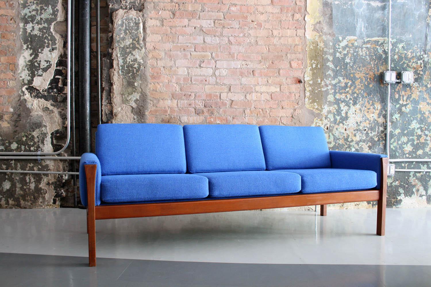 Original Hans Wegner design in teak and redone in a blue Maharam wool upholstery. All strapping and foam has been replaced and the frame has been restored to its original finish.