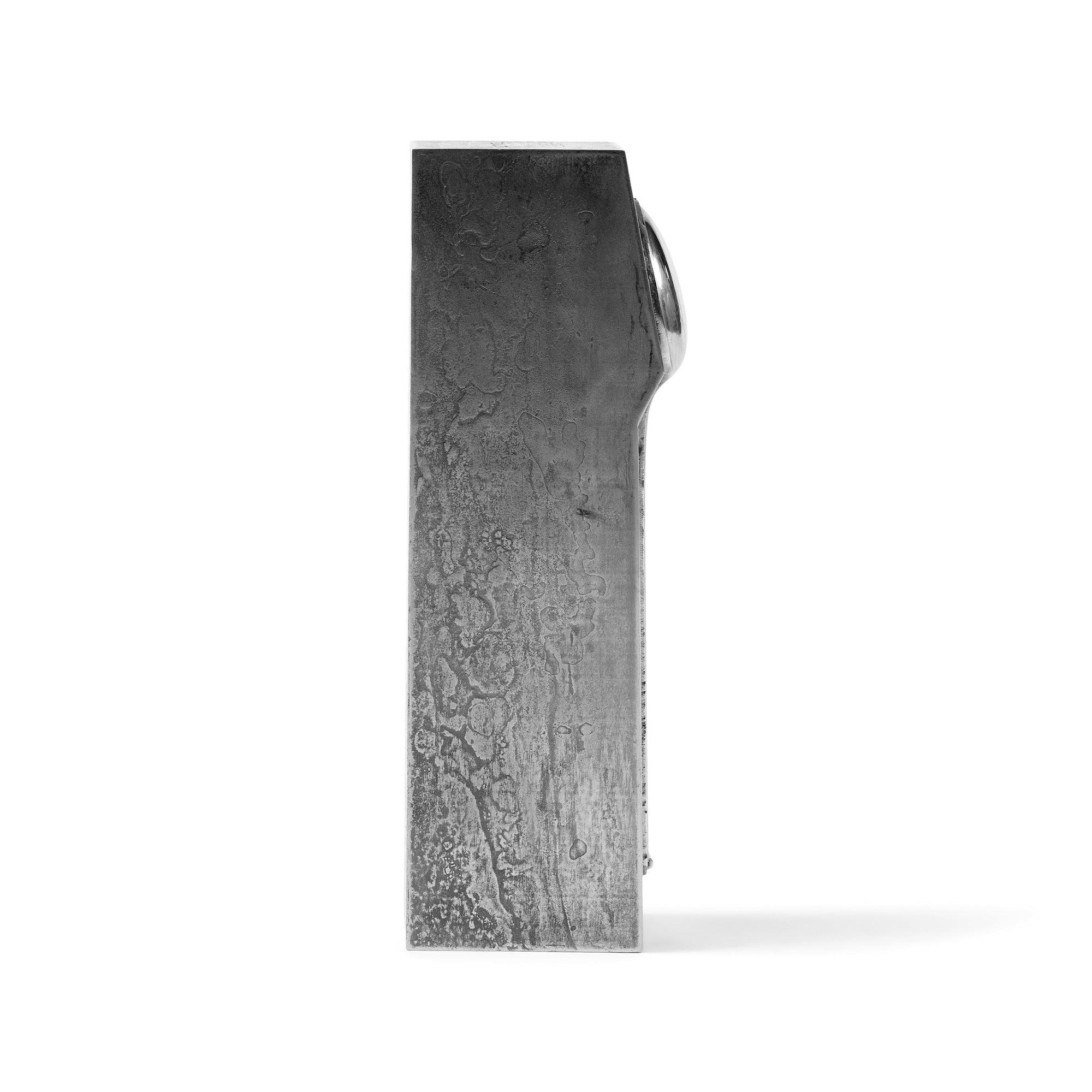 Une cuillère à thé en acier usiné qui peut être utilisée comme serre-livre ou sculpture.