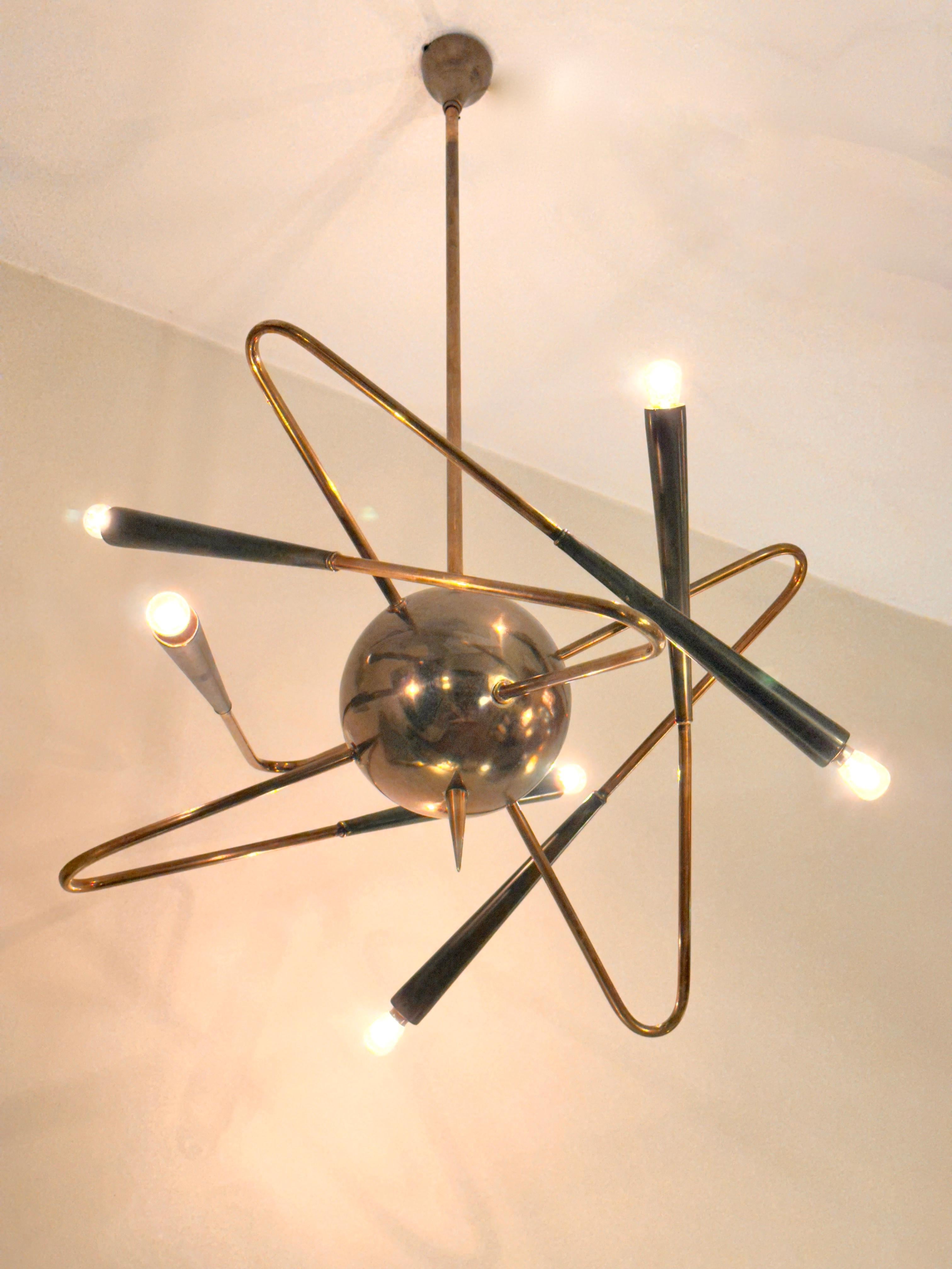 A Stilnovo Satellite chandelier/pendant edited in the 50s by Italian Stilnovo . Original lighting feature holing a central burnished brass medallion connected to a rigid brass rod.Design showing six brass curved armsevoking a satellite