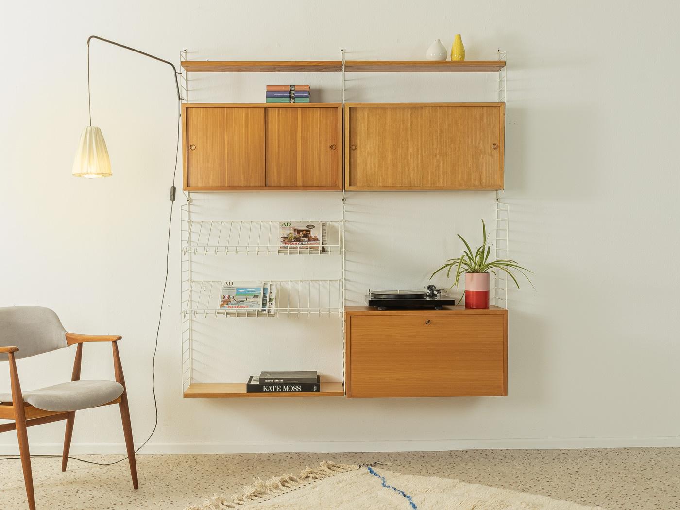 Original String shelf designed in 1949 by Nils Strinning in ash veneer. The system consists of six metal ladders in white with three shelves, two containers with sliding doors, one container with a flap door with many compartments and three internal