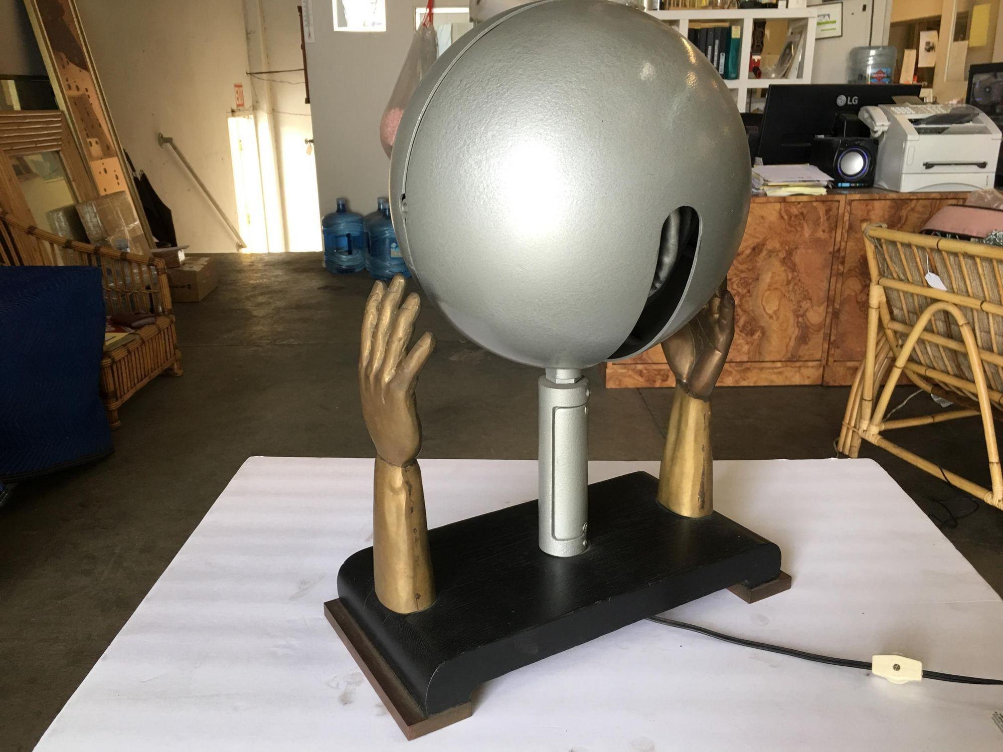 Original 1930's custom made table lamp featuring a pair of hand-cast bronze hands fixed to a lacquered wood base with a center spotlight. The spotlight takes a standard light bulb and is positional up and down and left to right.
