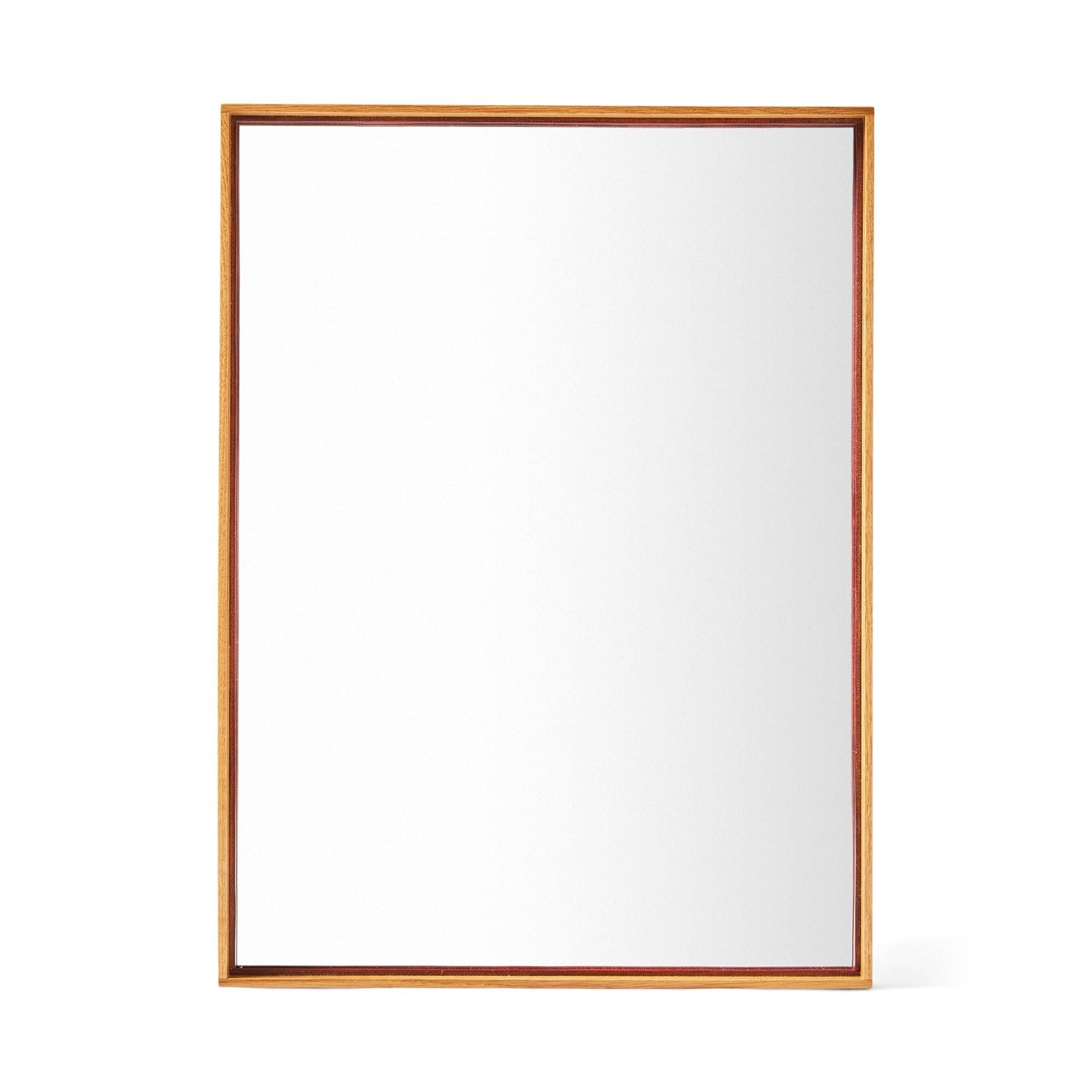 Miroir mural à bord fin assemblé en queue d'aronde avec un cadre en chêne fraisé. Il peut être suspendu horizontalement ou verticalement.