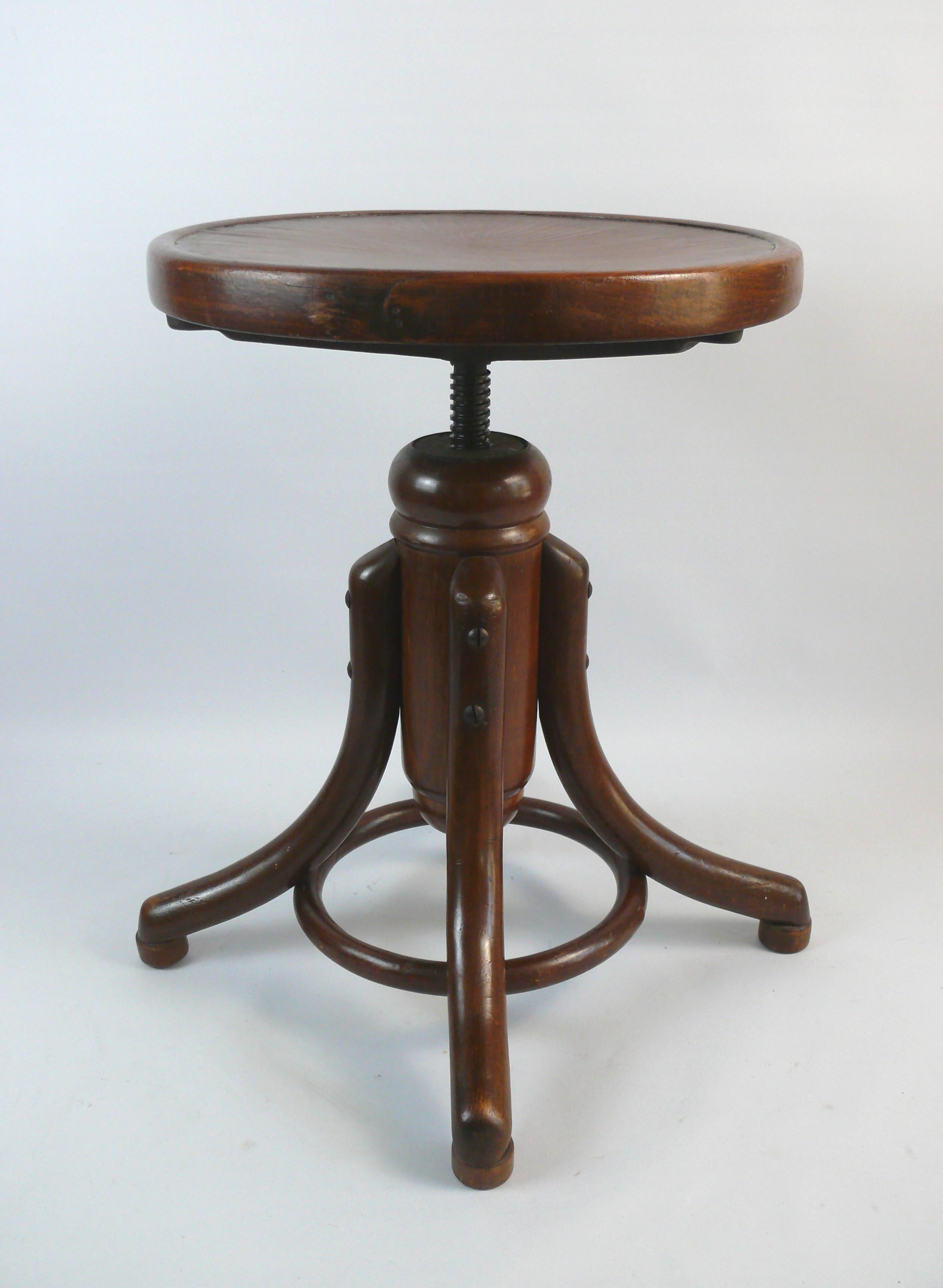 Antique piano stool/swivel stool by Gebrüder Thonet. The piano stool is made of stained and shellac-lacquered beech wood and has four steam-bent feet with a bentwood ring for stability. The stool can be adjusted in height from 46 cm to approx. 65