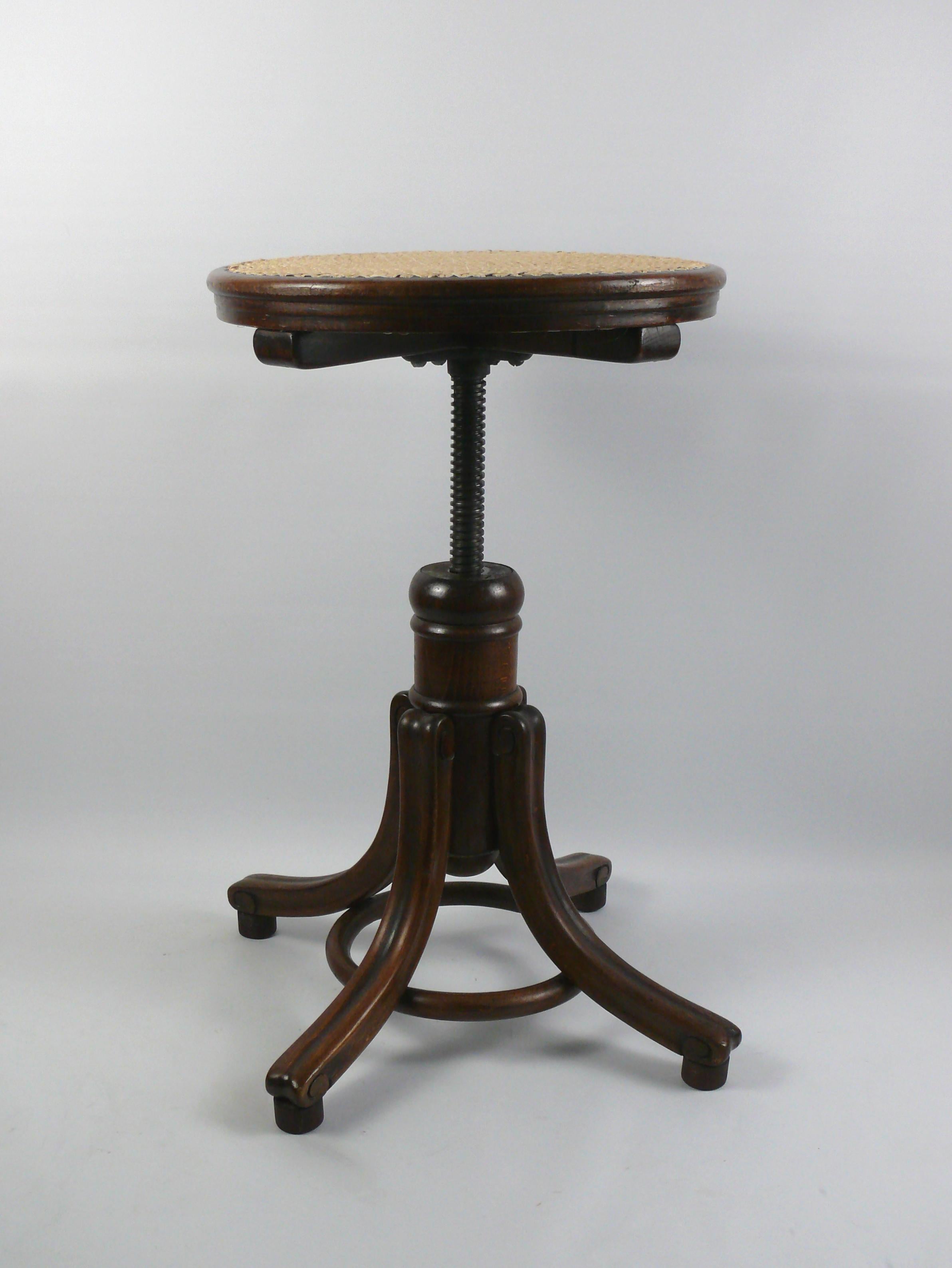 Piano stool by the traditional company Gebrüder Thonet, Vienna from the late 19th or early 20th century. The piano stool is made of solid wood and has a frame with a bentwood ring. The curved feet are held together by the wooden ring made of curved
