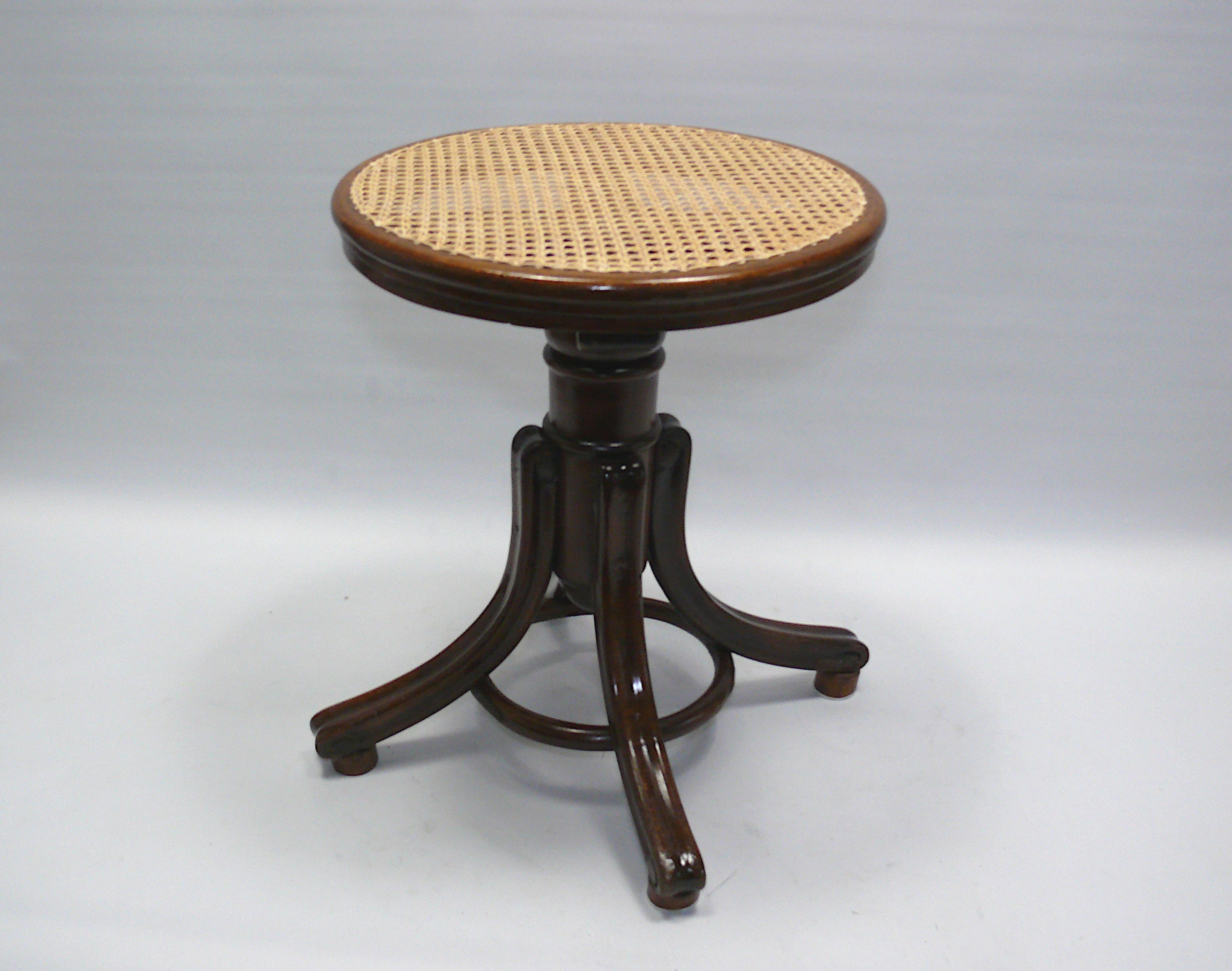 Piano stool by the traditional company Gebrüder Thonet, Vienna from the late 19th or early 20th century. The piano stool is made of solid wood and has a frame with a bentwood ring. The curved feet are held together by the wooden ring made of curved
