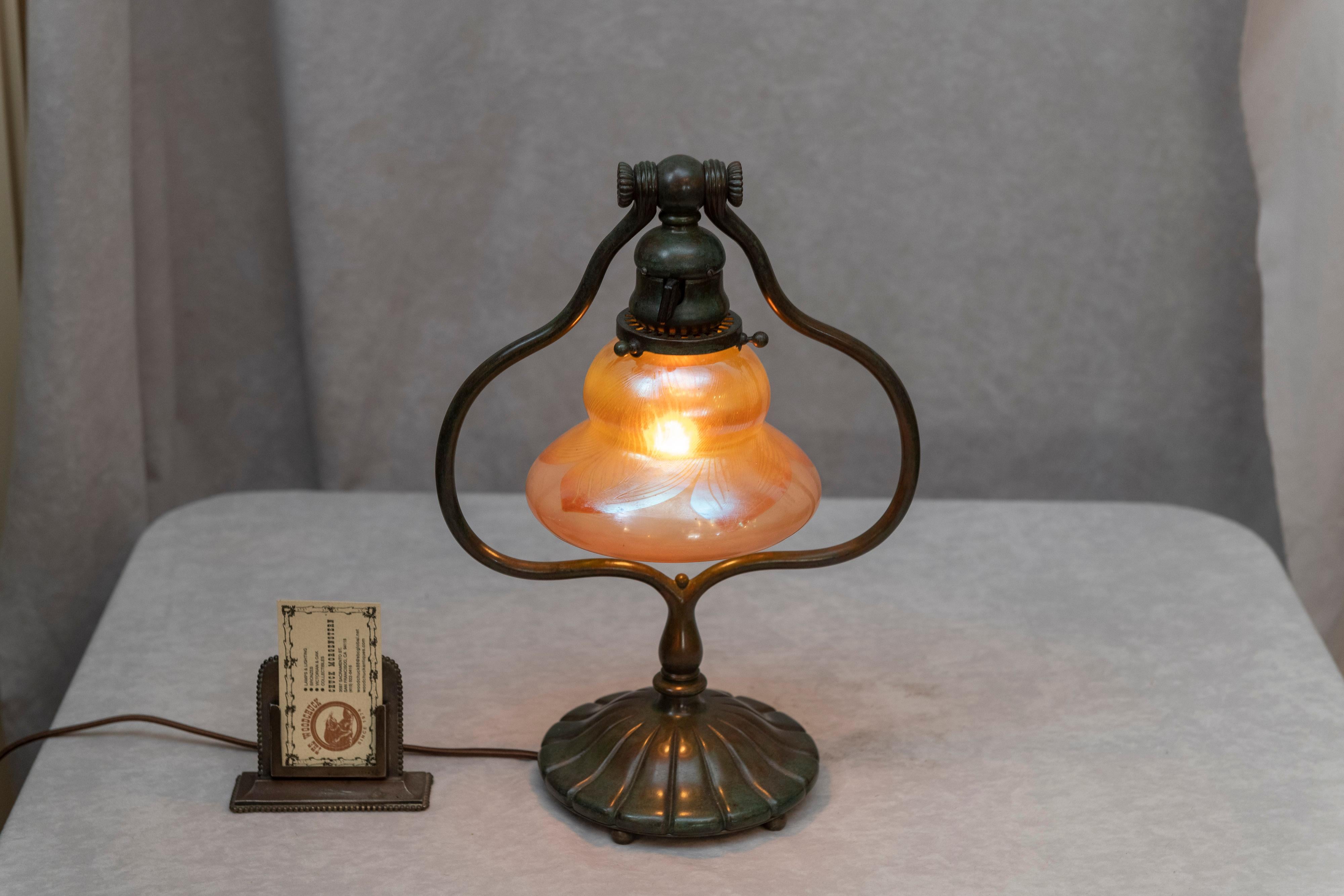 This is a real Tiffany Studios Lamp. The bronze base which supports the shade can be adjusted to the angle of your preference, circa 1905. The shade is signed 