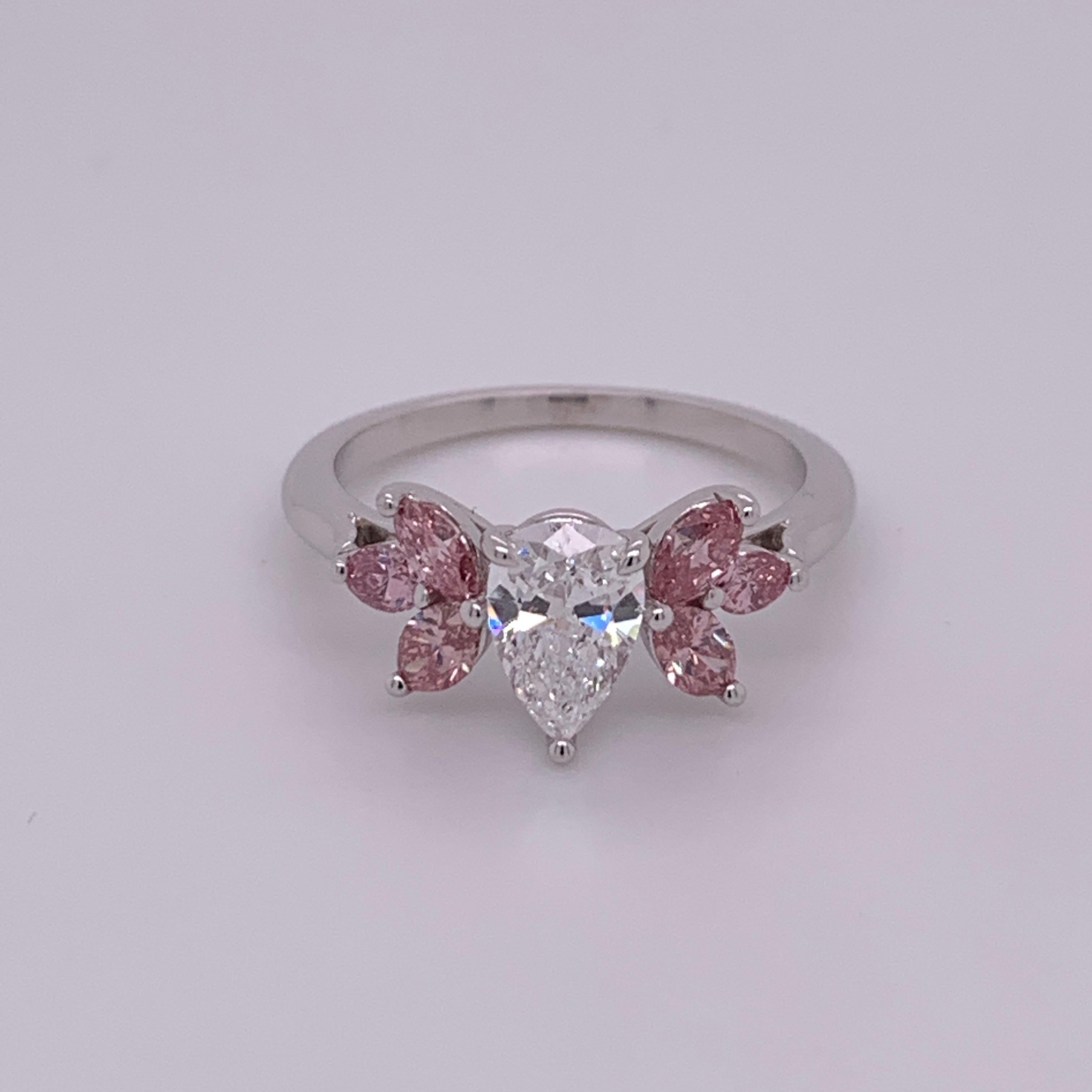 Magnificent Platinum Ring set with a colorless Pear shaped centerstone (appx 1 carat, 8x5mm) as well as six Natural Marquise Pink Diamonds (certified by GIA as natural). The color is estimated to be “vivid” or “deep” pink. (Appx 0.75 carat,