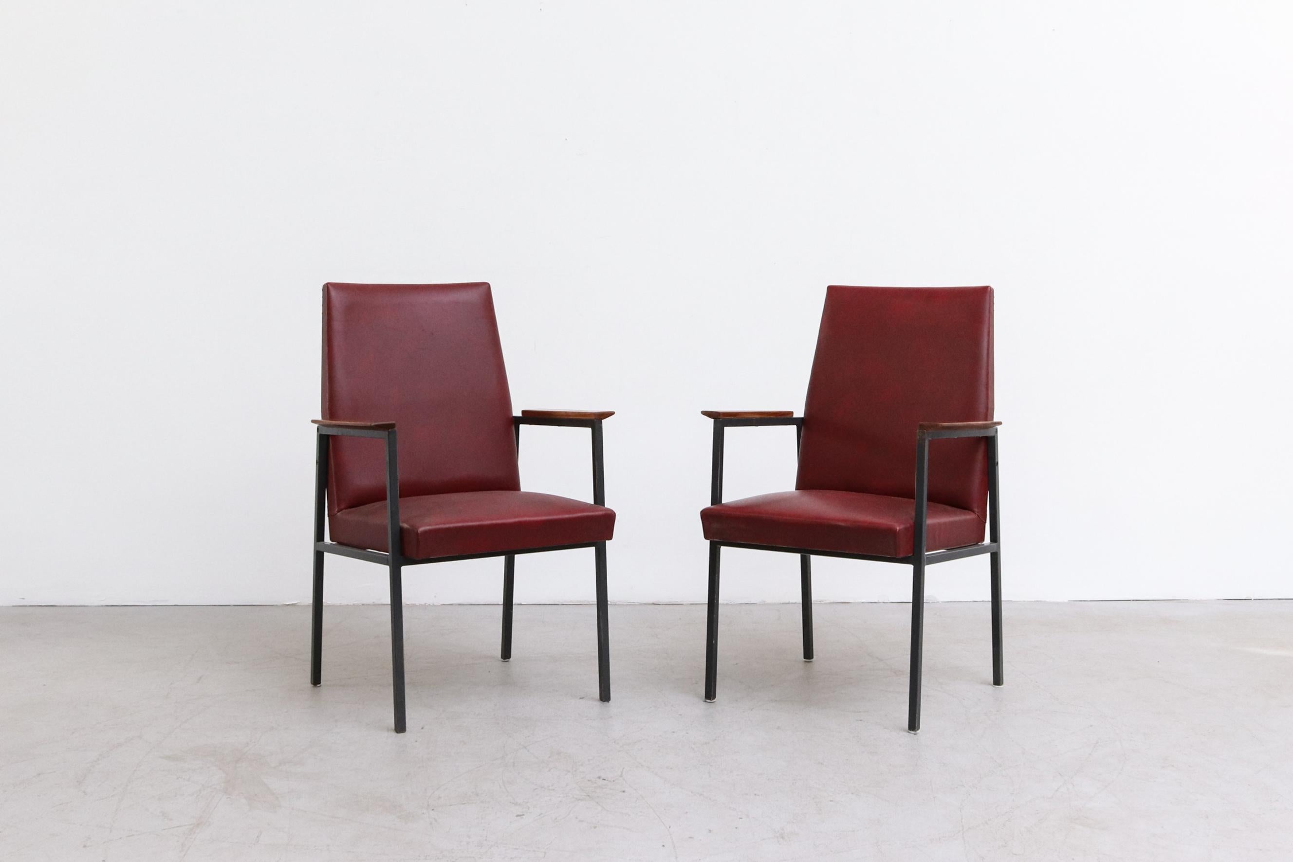 High back Tijsselling lounge chairs with enameled metal frame, teak armrests and original burgundy skai upholstery and red studded detail. Measure: Seat width is 19.5