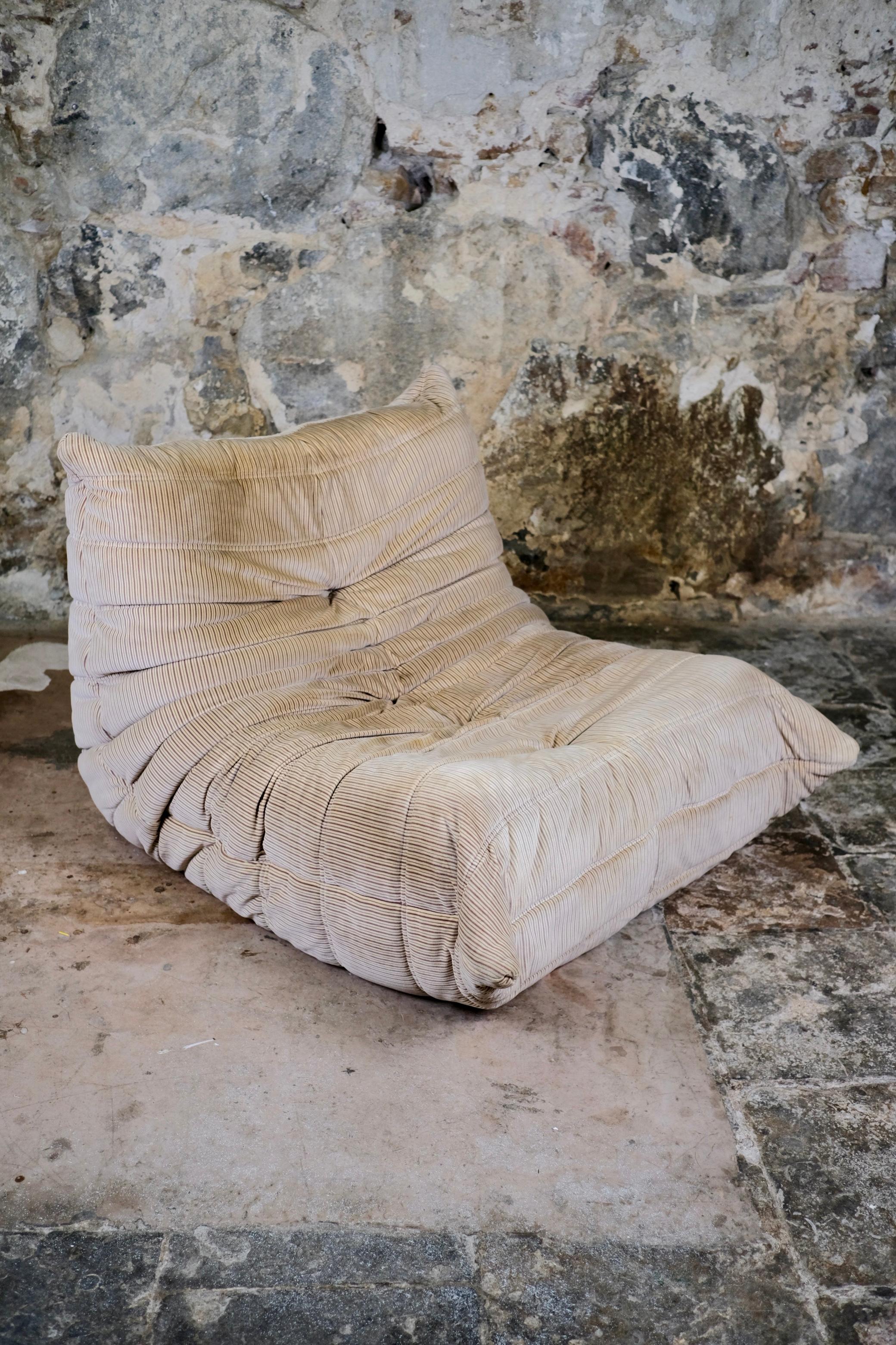 Tumbona Togo de Michel Ducaroy para Ligne Roset, principios de los años setenta.
En su tapicería original, un terciopelo con suave textura de piel de melocotón, que presenta elegantes rayas verticales en marrón satinado sobre fondo beige.

Auténtico