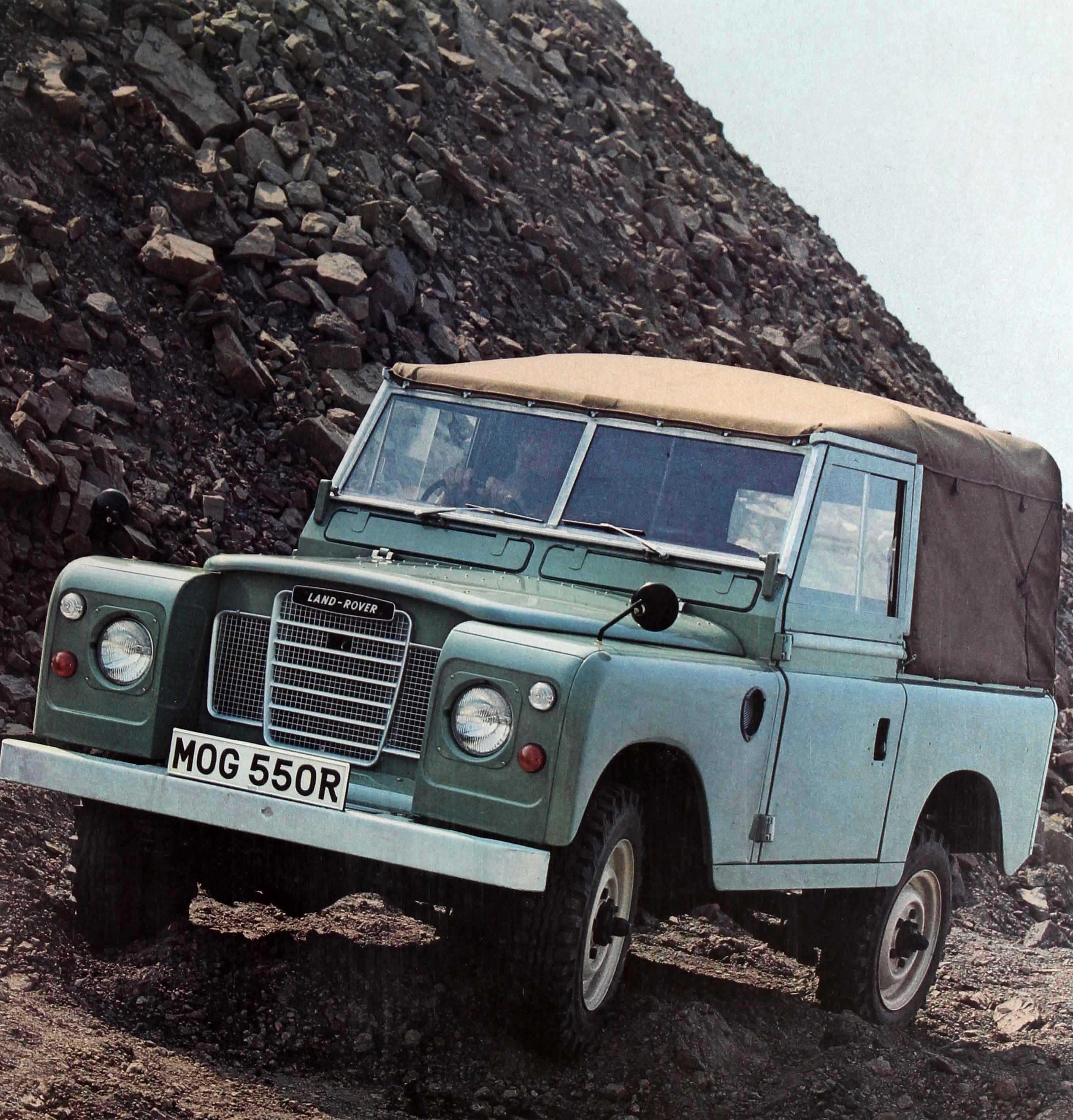 Original vintage Land Rover car advertising poster featuring a color photograph of a green Land Rover series III with the registration MOG 550 R driving through a rocky quarry with the heading in bold white letters below next to the Leyland logo in