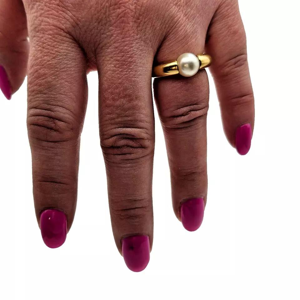 Este anillo Original Cartier presenta una impresionante banda de oro amarillo de 18 quilates y una perla Akoya redonda como piedra principal. La perla es natural y no ha sido mejorada de ninguna manera. El estilo de engaste es de tensión y la talla