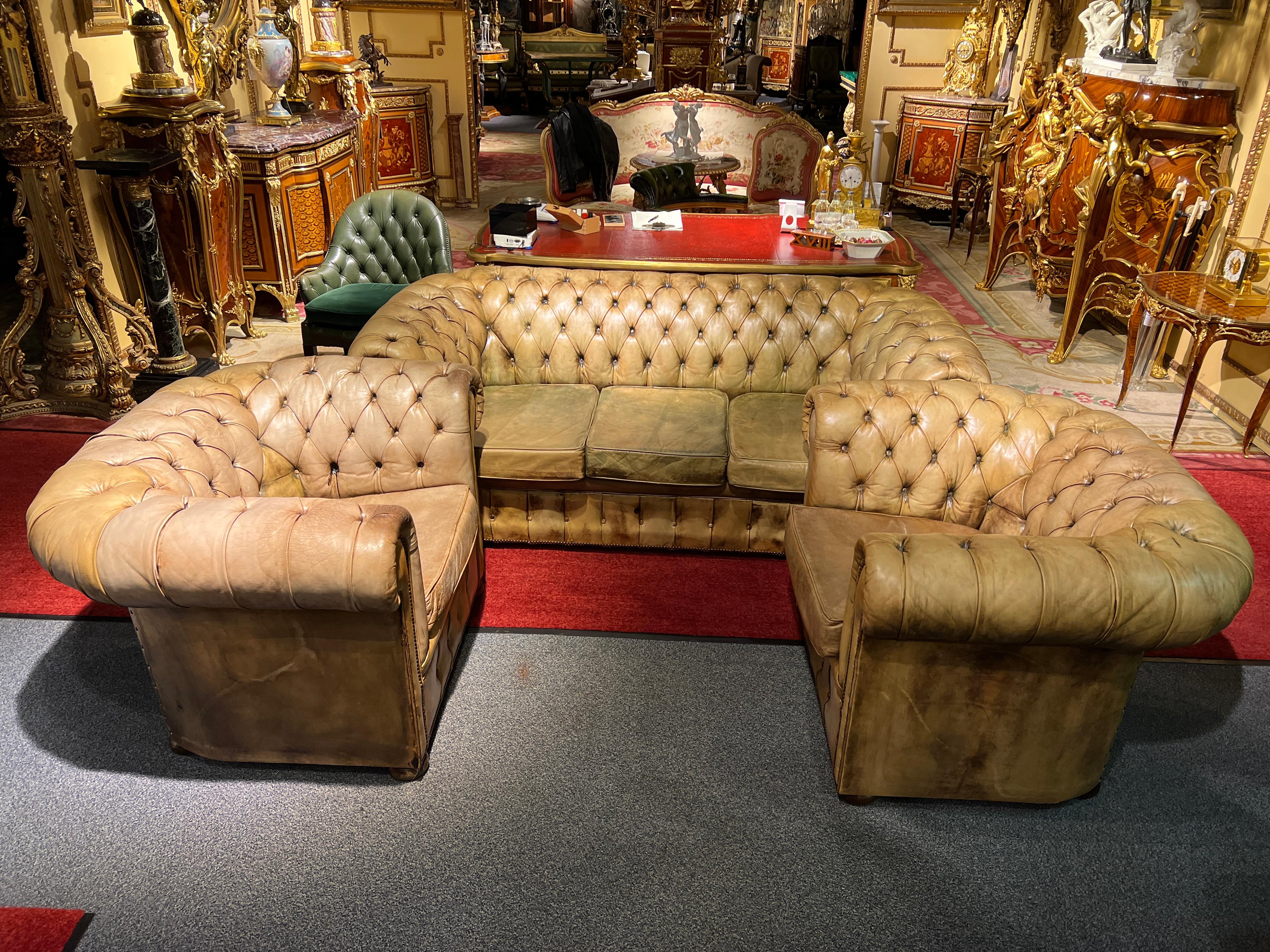 Cet ensemble en cuir Chesterfield se compose d'un élégant canapé 3 places et de deux fauteuils assortis, créant un charme luxueux et intemporel. Les pièces présentent le rembourrage Chesterfield caractéristique avec des boutons profonds et arrondis