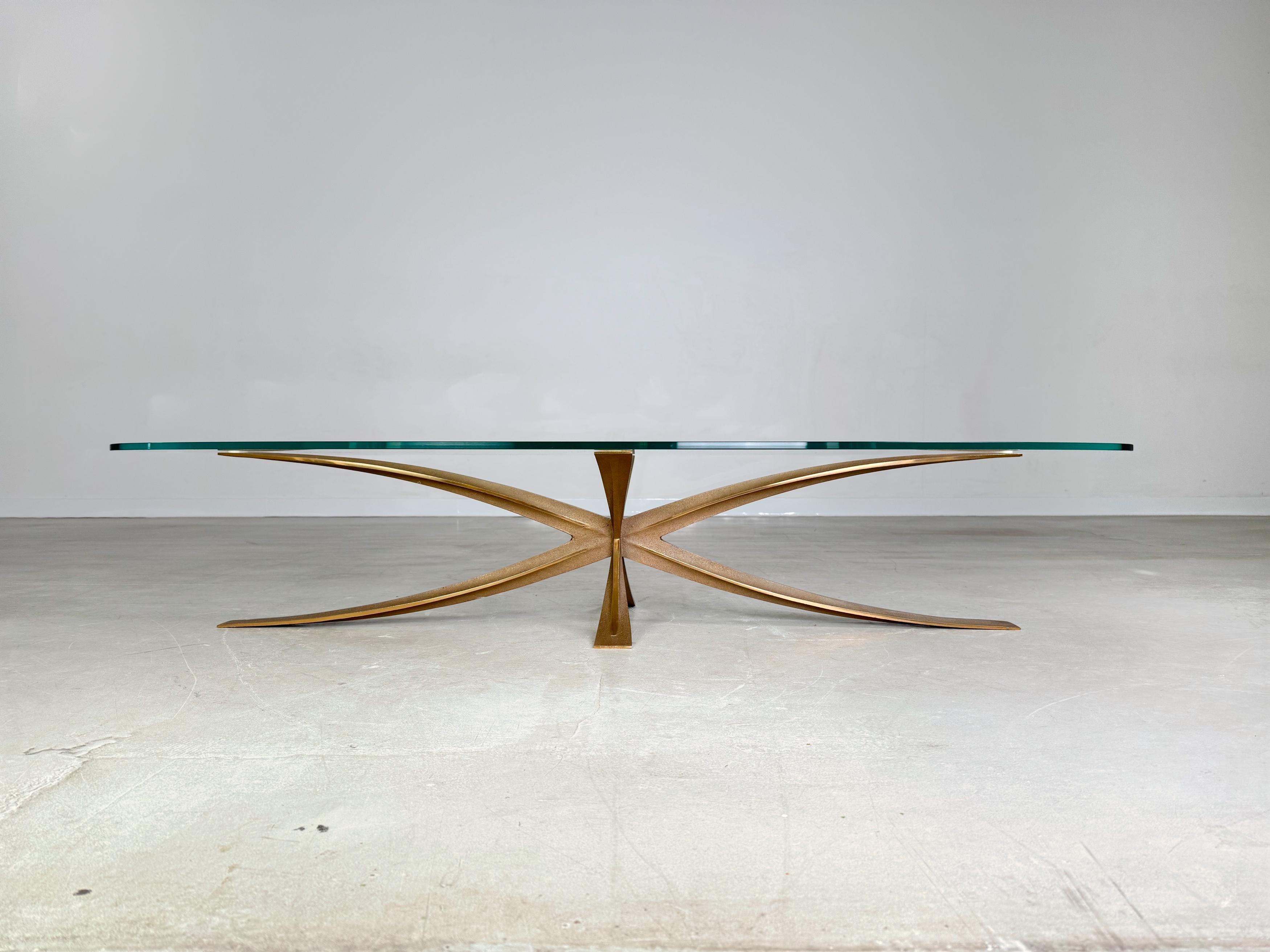 Wir bieten einen wunderschönen Couchtisch von Michel Mangematin zum Verkauf an. Der ovale Tisch verfügt über ein sternenförmiges Gestell aus Bronze und einer komplett neuen, originalgetreuen Tischplatte. Mangematin war Architekt und Designer und